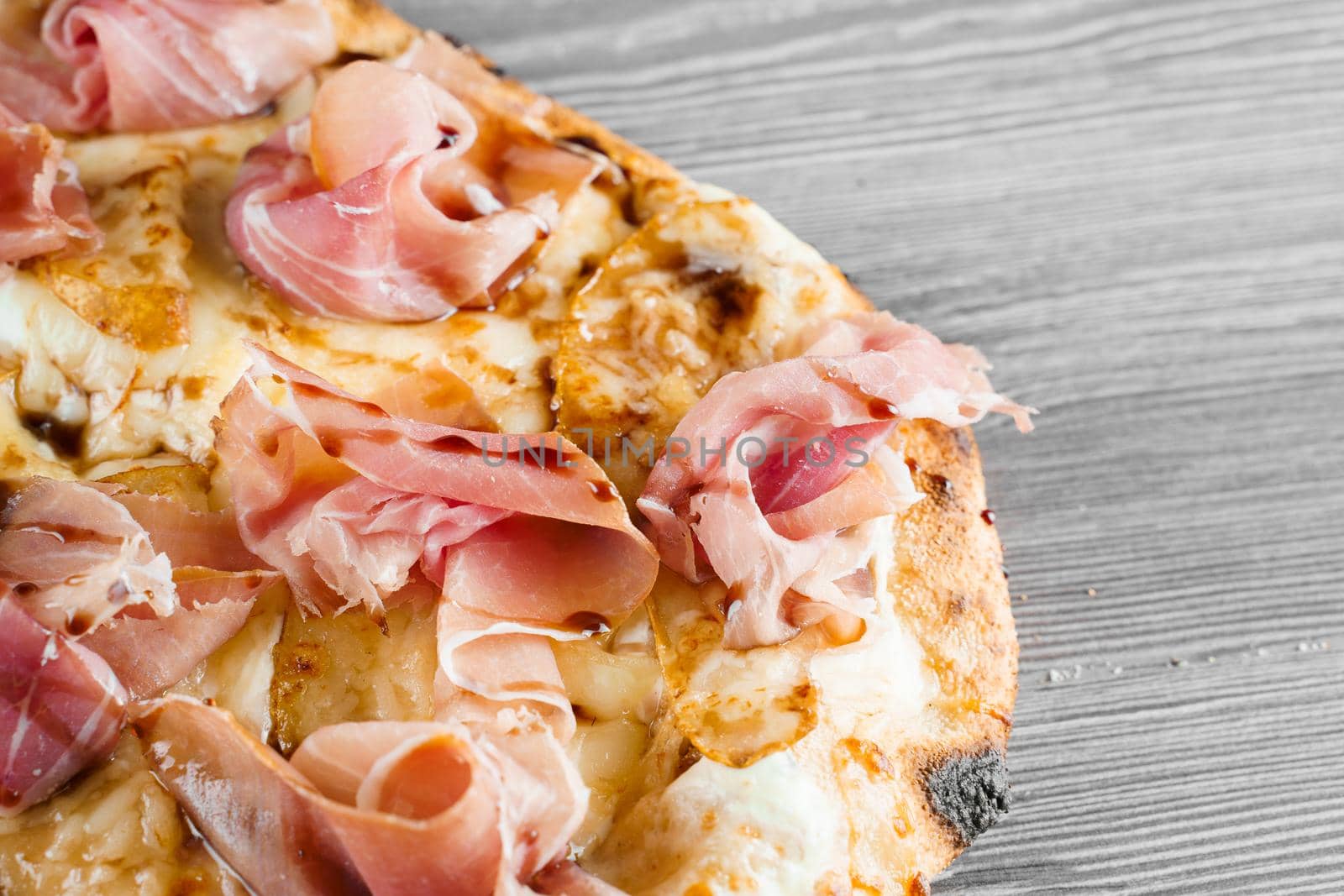 Scrocchiarella with pear, cheese, prosciutto on grey wooden background. Pinsa romana gourmet italian cuisine. Junk food by Rabizo