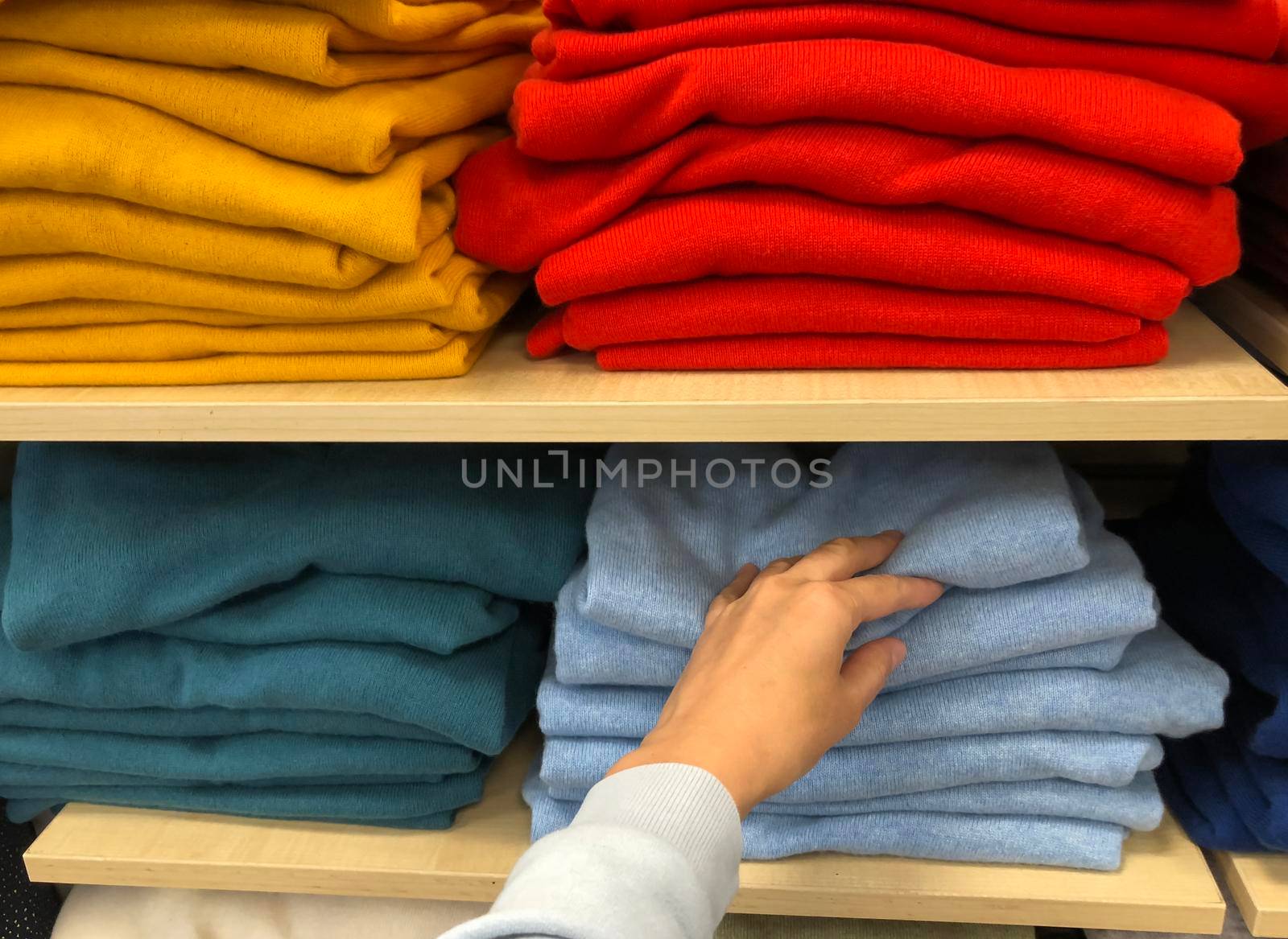 Rows of folded colorful clothes in a shop