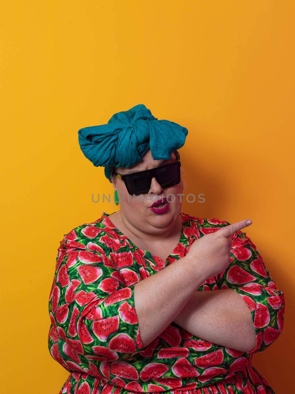 Funny plus size sexy model woman with trendy sunglasses, fashionable overweight blonde in colorful dress posing at the yellow fortuna gold background in studio. High quality photo