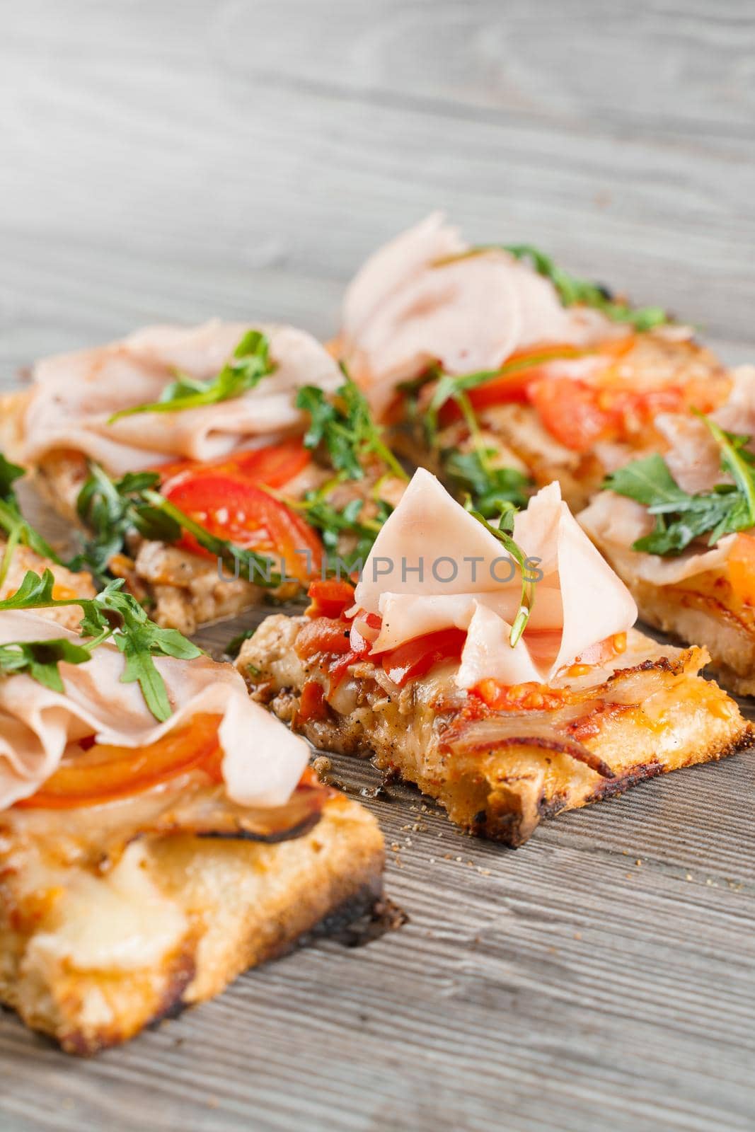 Pinsa romana cut into pieces portions for one person. Food delivery from pizzeria. Pinsa with meat, arugula, cheese. by Rabizo