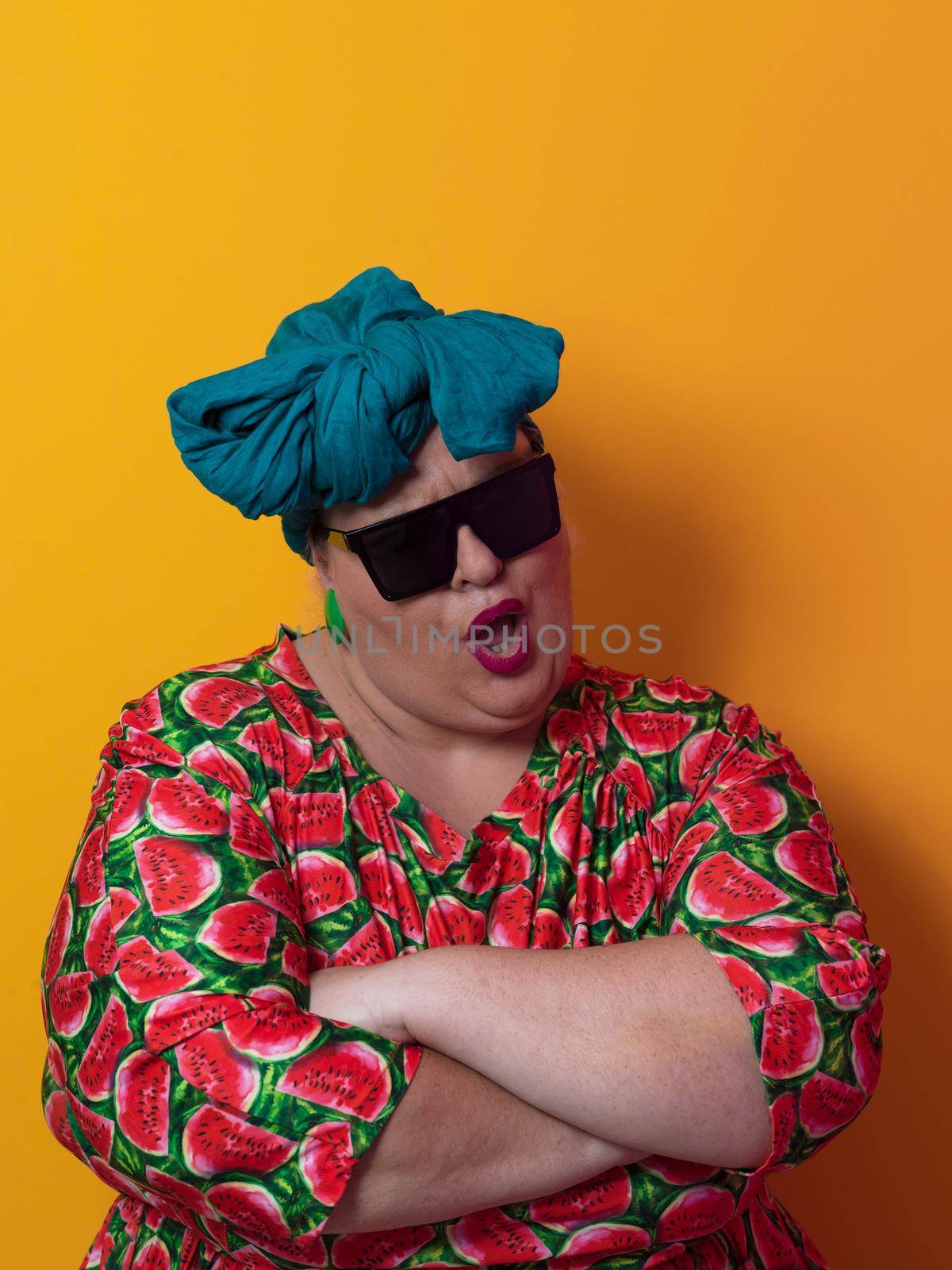 Funny plus size sexy model woman with trendy sunglasses, fashionable overweight blonde in colorful dress posing at the yellow fortuna gold background in studio. High quality photo