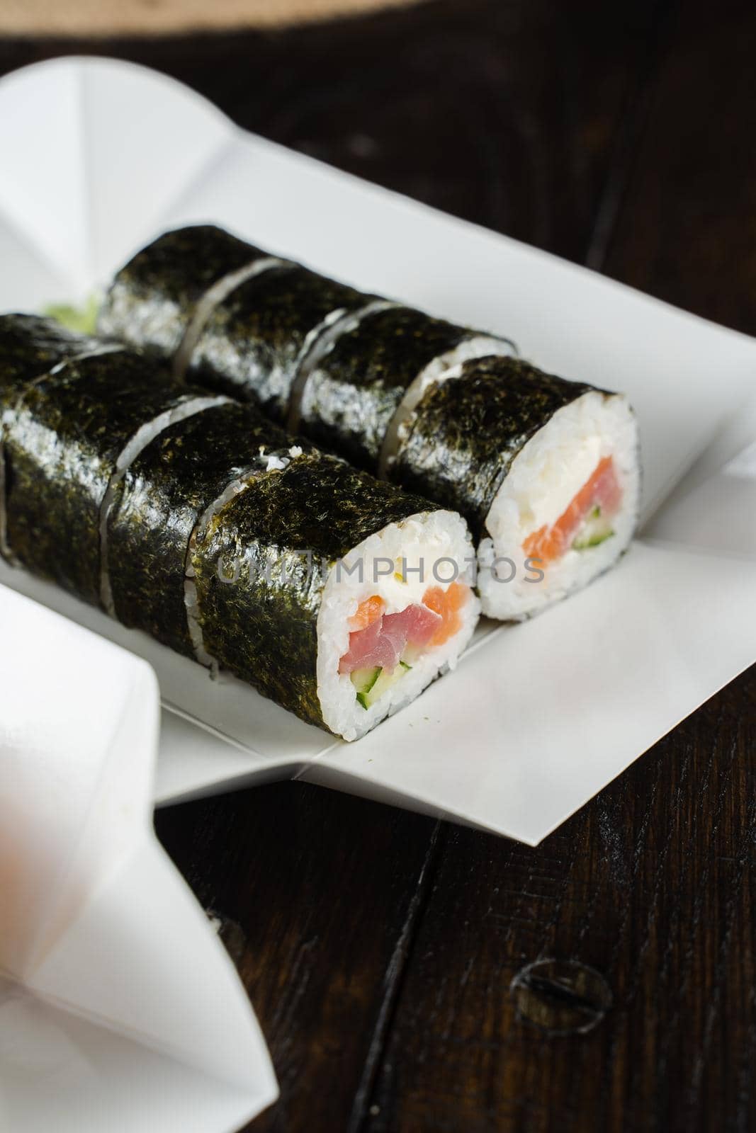 Sushi roll on the food delivery plate. Roll with salmon, tuna, cucumber and soft cheese. by Rabizo