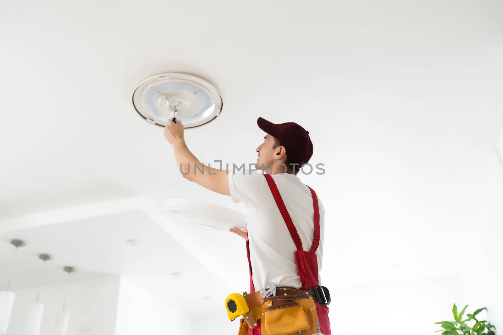 Electrician installs a chandelier on the ceiling. Construction concept.