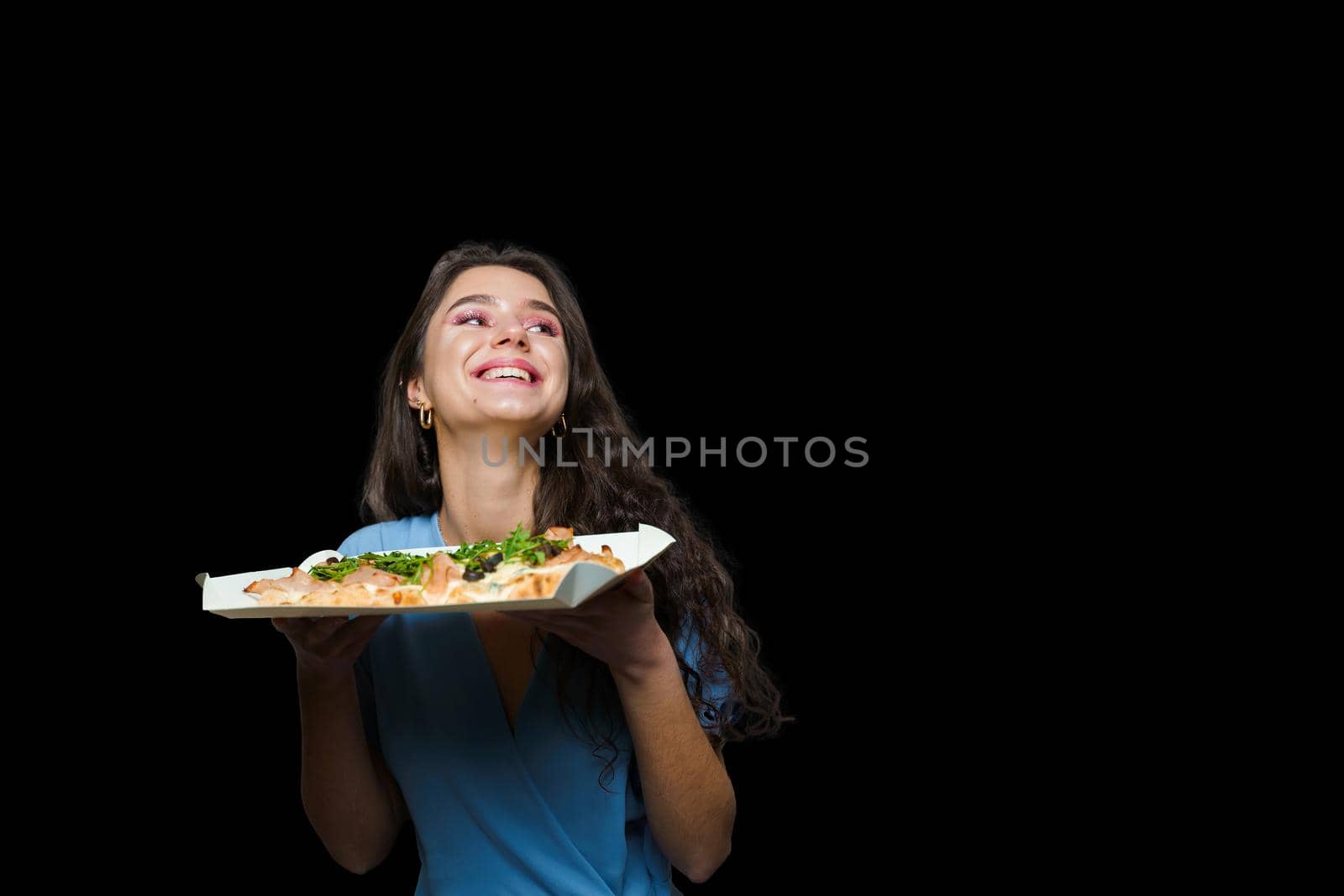 Woman courier with pinsa romana gourmet italian cuisine on black background. Holding scrocchiarella traditional dish. Food delivery from pizzeria. Pinsa with meat, arugula, olives, cheese