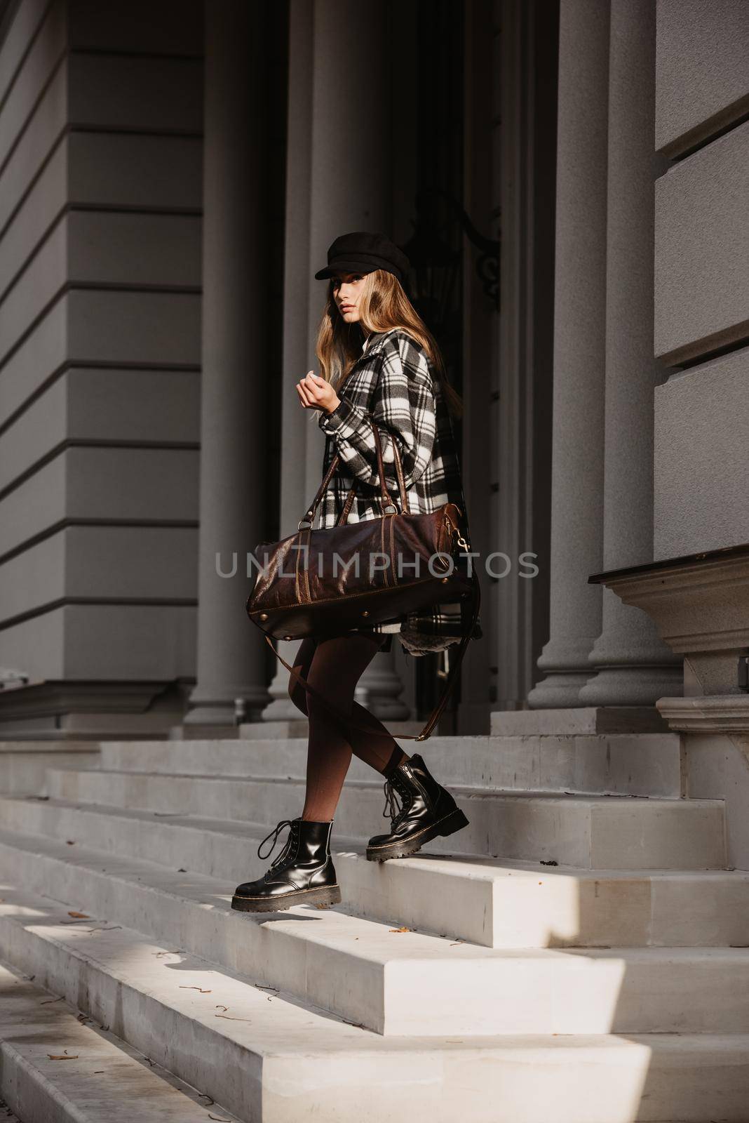 Outdoor fashion portrait of young beautiful fashionable girl wearing trendy checkered shirt. solid long sleeve bodycon one piece jumpsuits. small brown color small bag, posing in street.