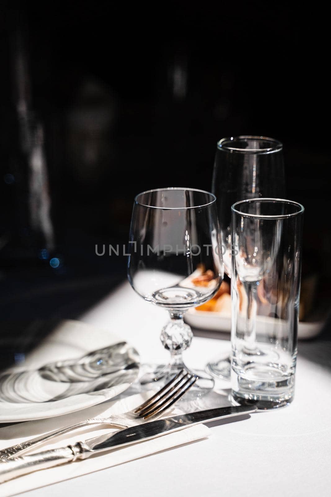 Glasses, plate and cutlery on the table. Table setting in the restaurant. by Rabizo