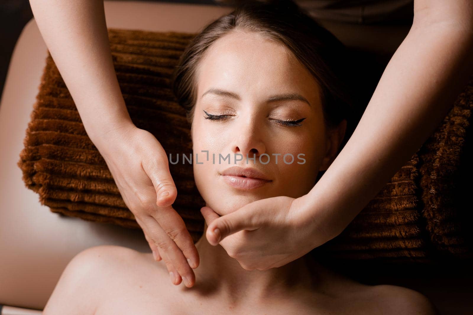 Neck and face massage in the spa. Masseur is making facial beauty treatments for an attractive female model. Relaxation