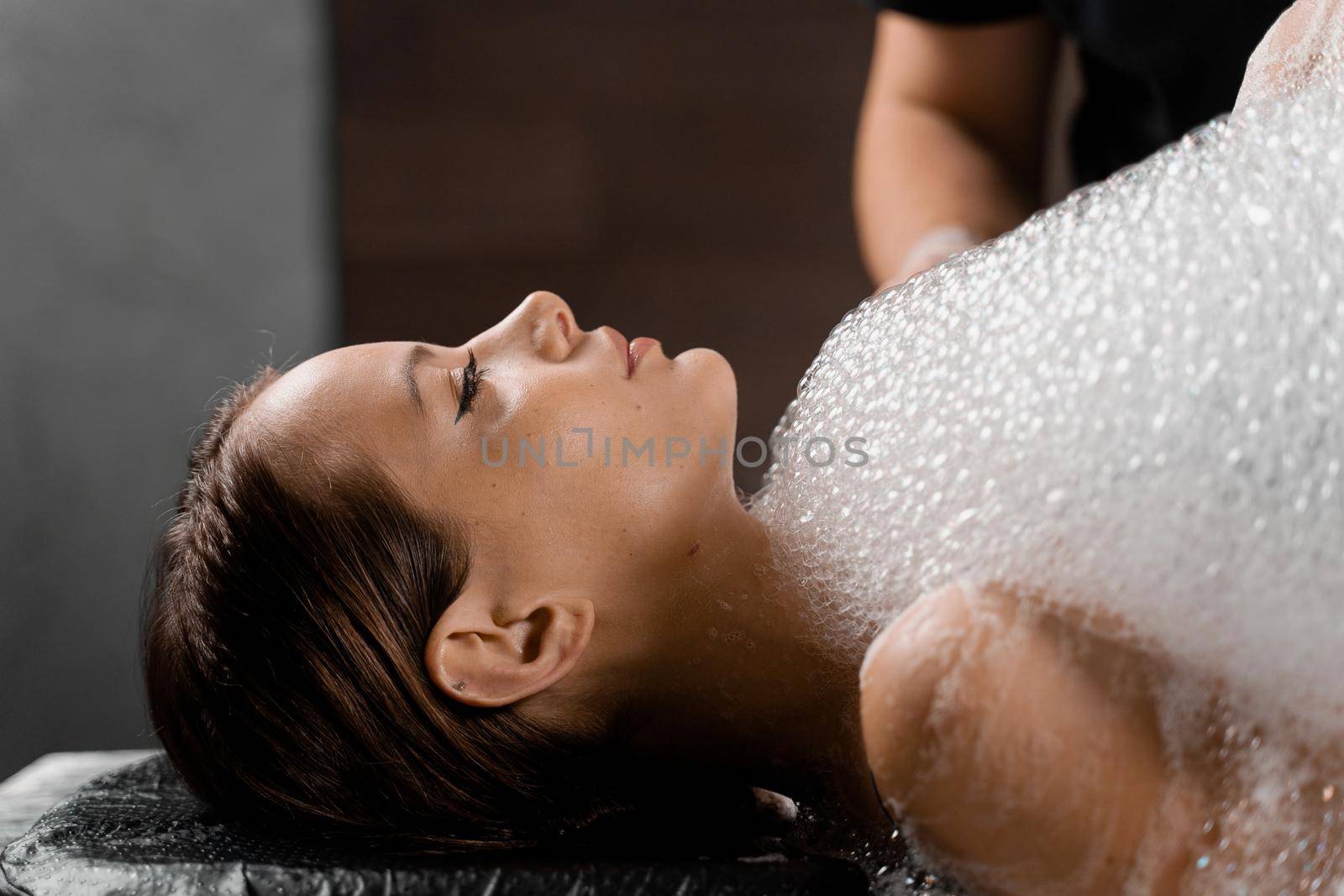 Close-up foam peeling massage for model in spa. Relaxation in Turkish hammam.