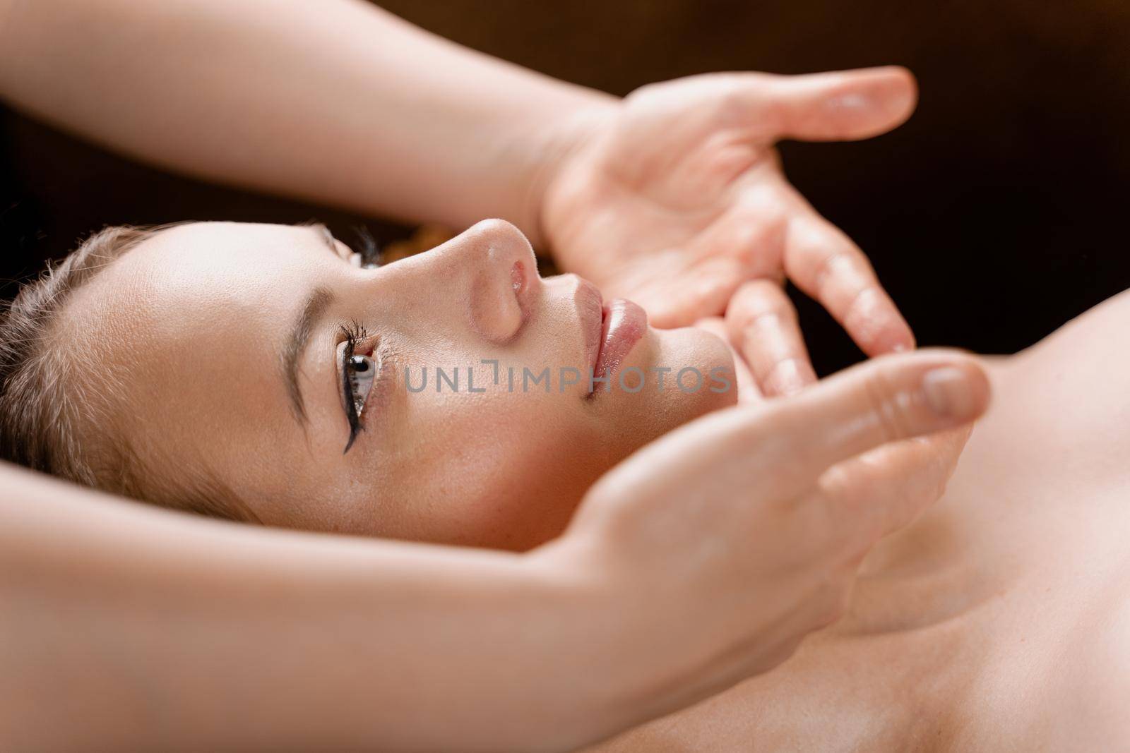 Facial massage close-up in spa center. Girl with perfect skin relaxing in massage room