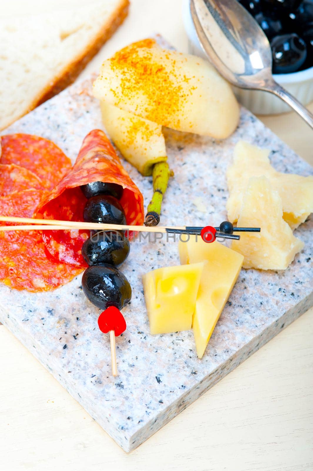 cold cut assortment cheese salami and fresh pears served on a granite stone