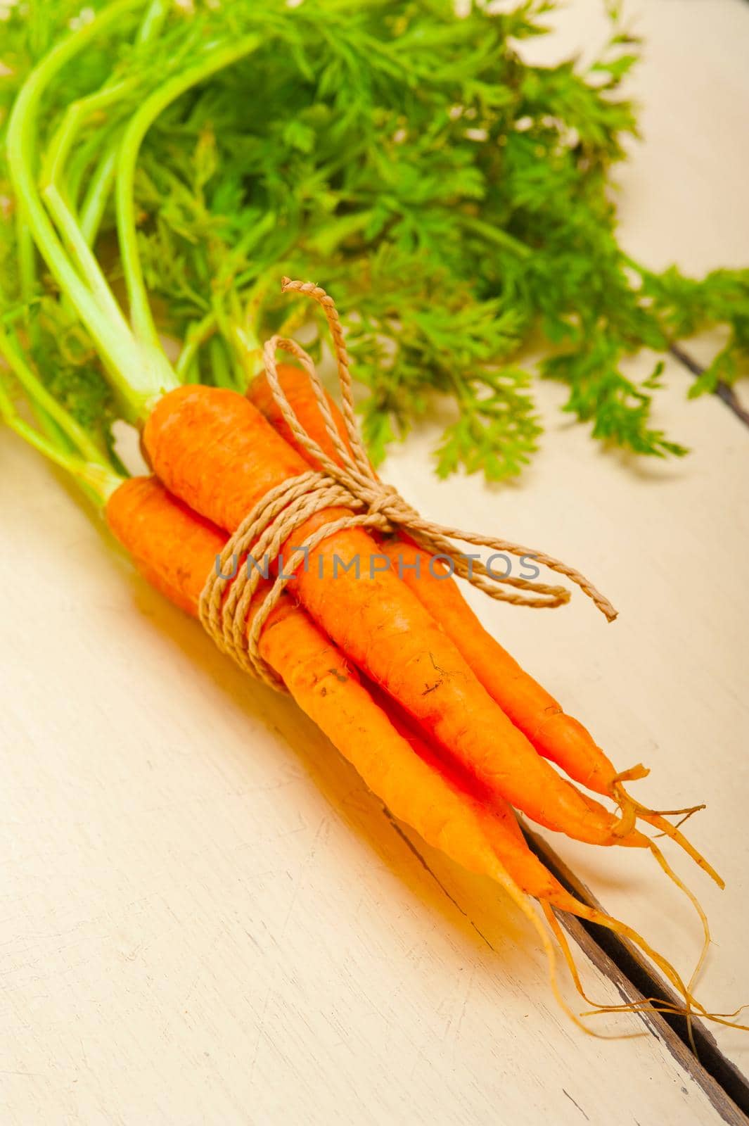 fresh baby carrots bunch tied with rope on a rustic table