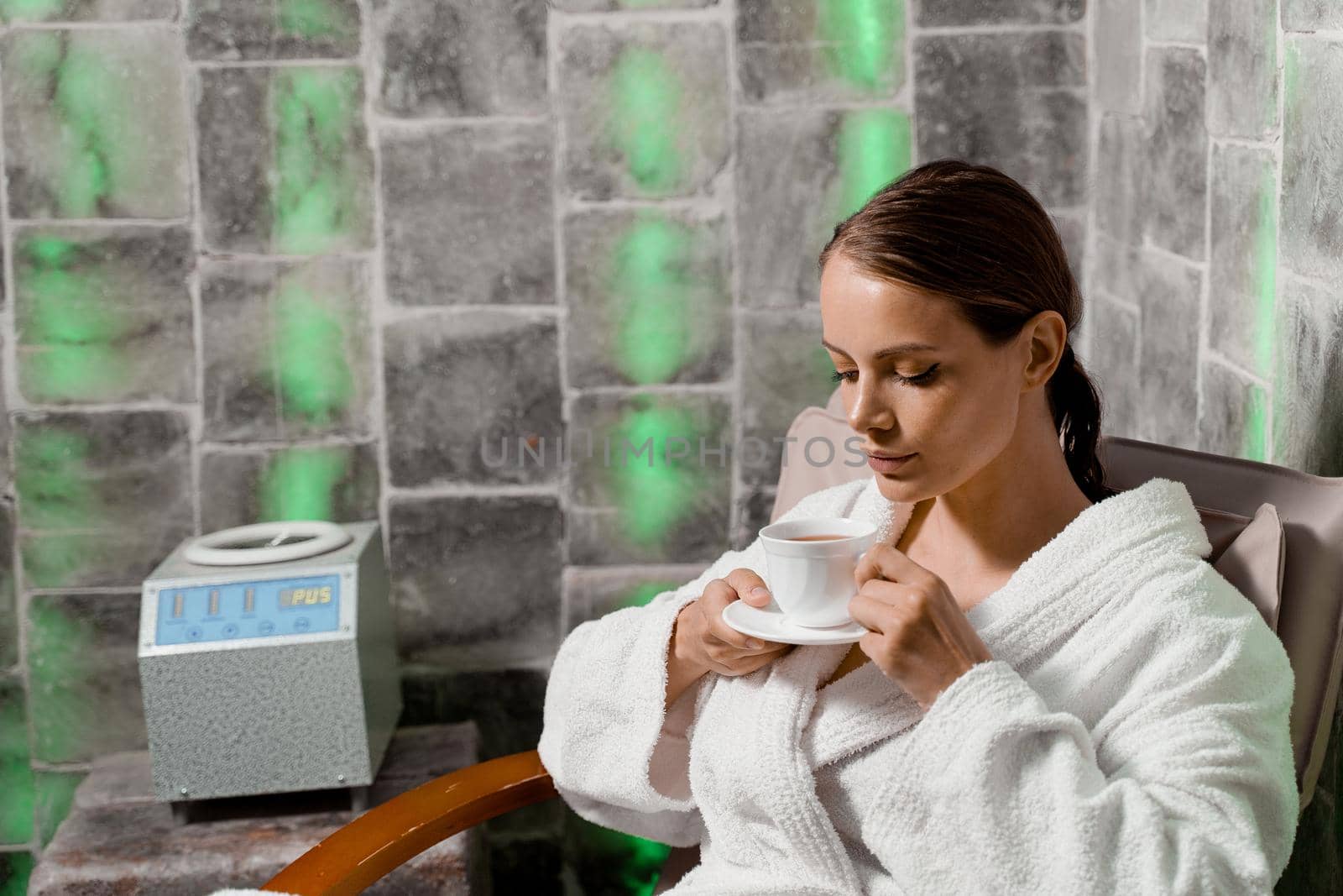 Inhalation therapy in salt room in spa. Young woman with cup of tea relaxing. by Rabizo