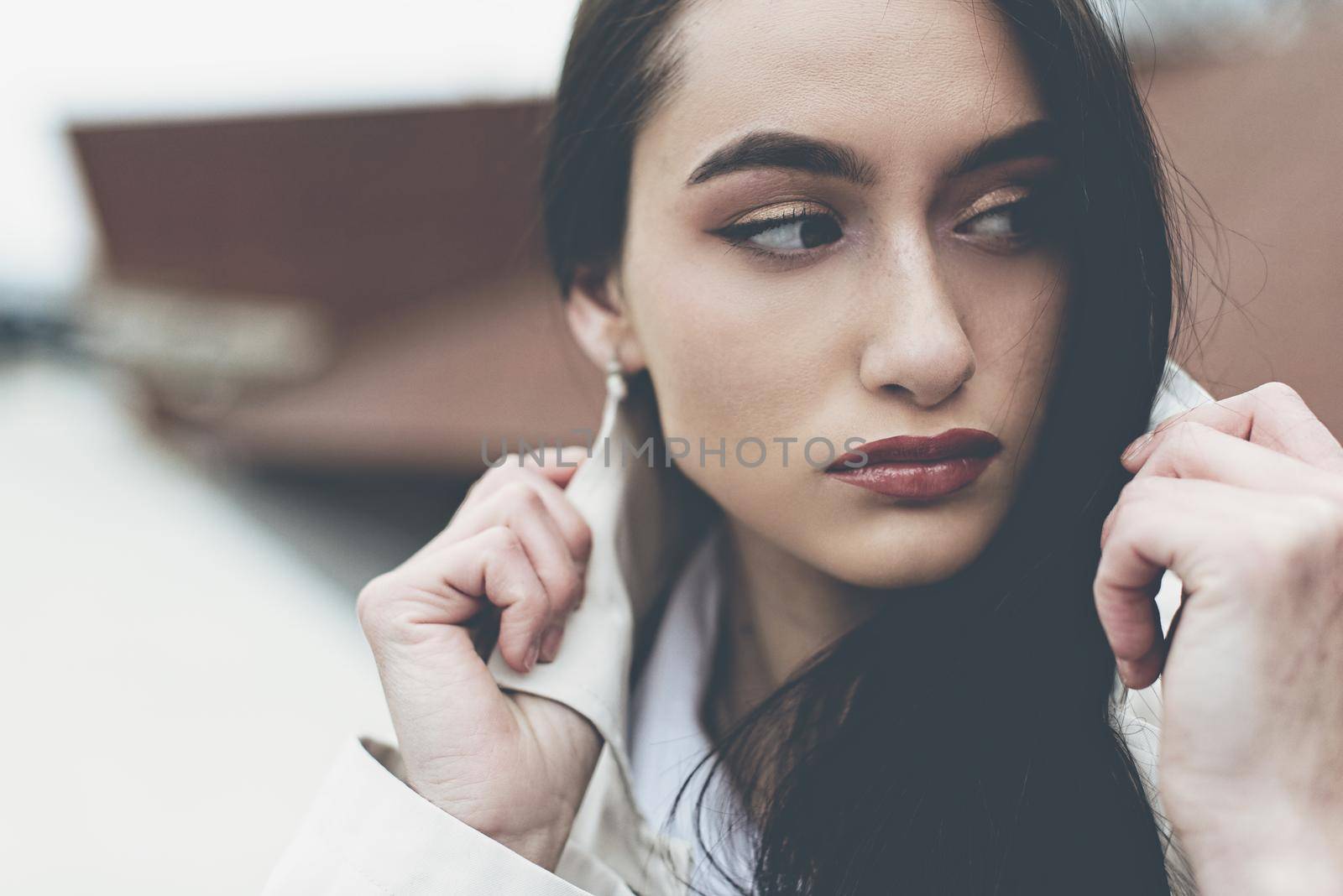 Outdoor portrait of a young beautiful fashionable lady wearing stylish coat . Model looking aside. Female fashion concept. City lifestyle. Close up. big plump lips