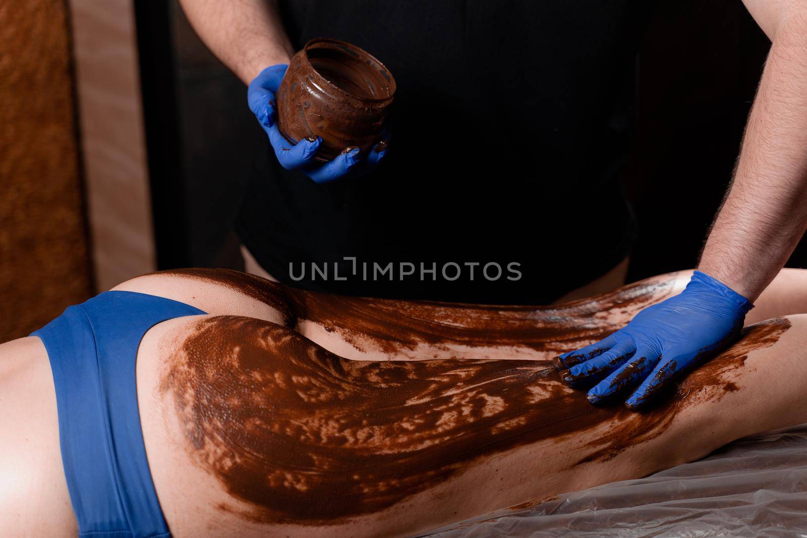 Chocolate massage for legs and hips of young woman. Chocolate wrap spa treatment. by Rabizo