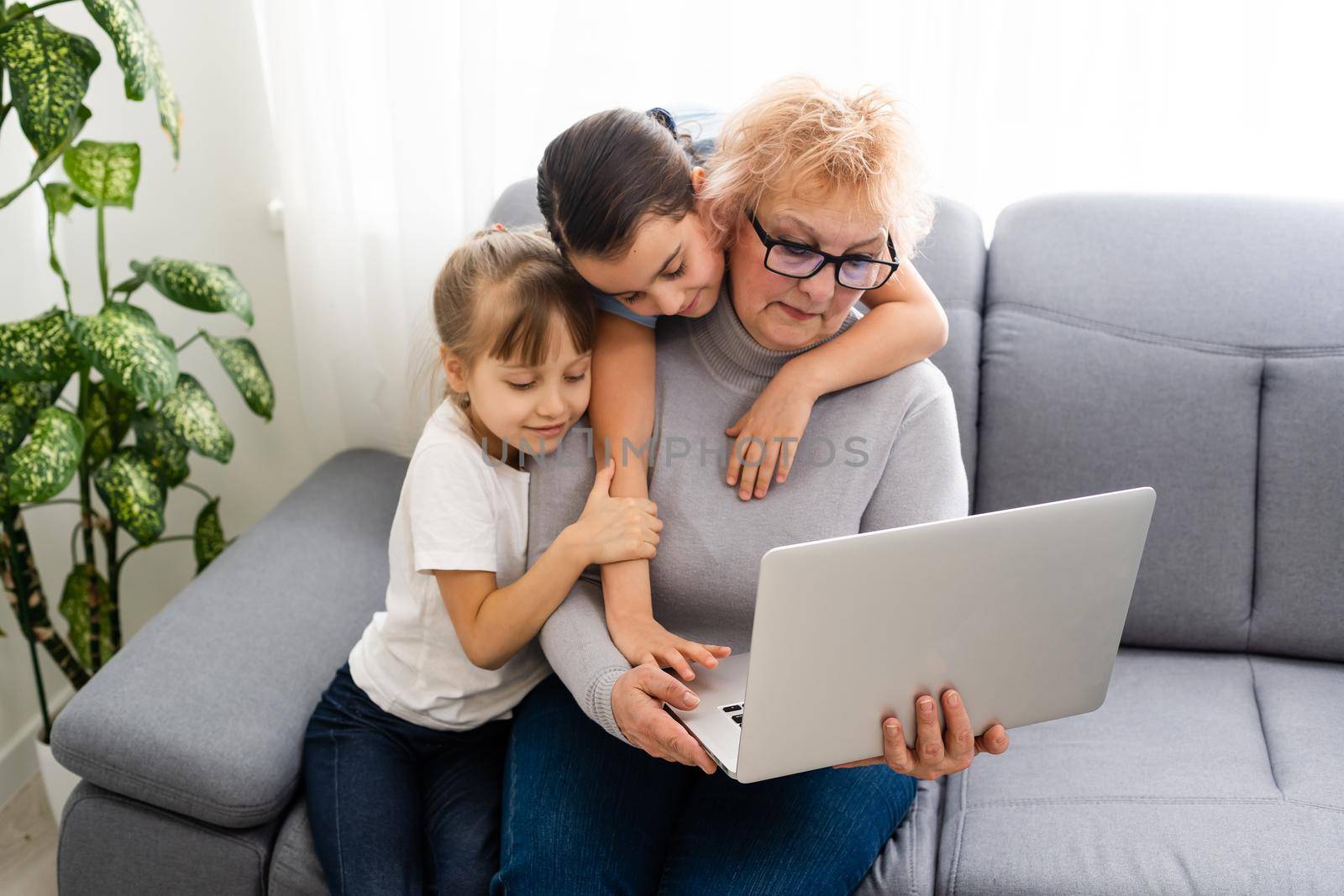 Grandmother with granddaughters use a computer.