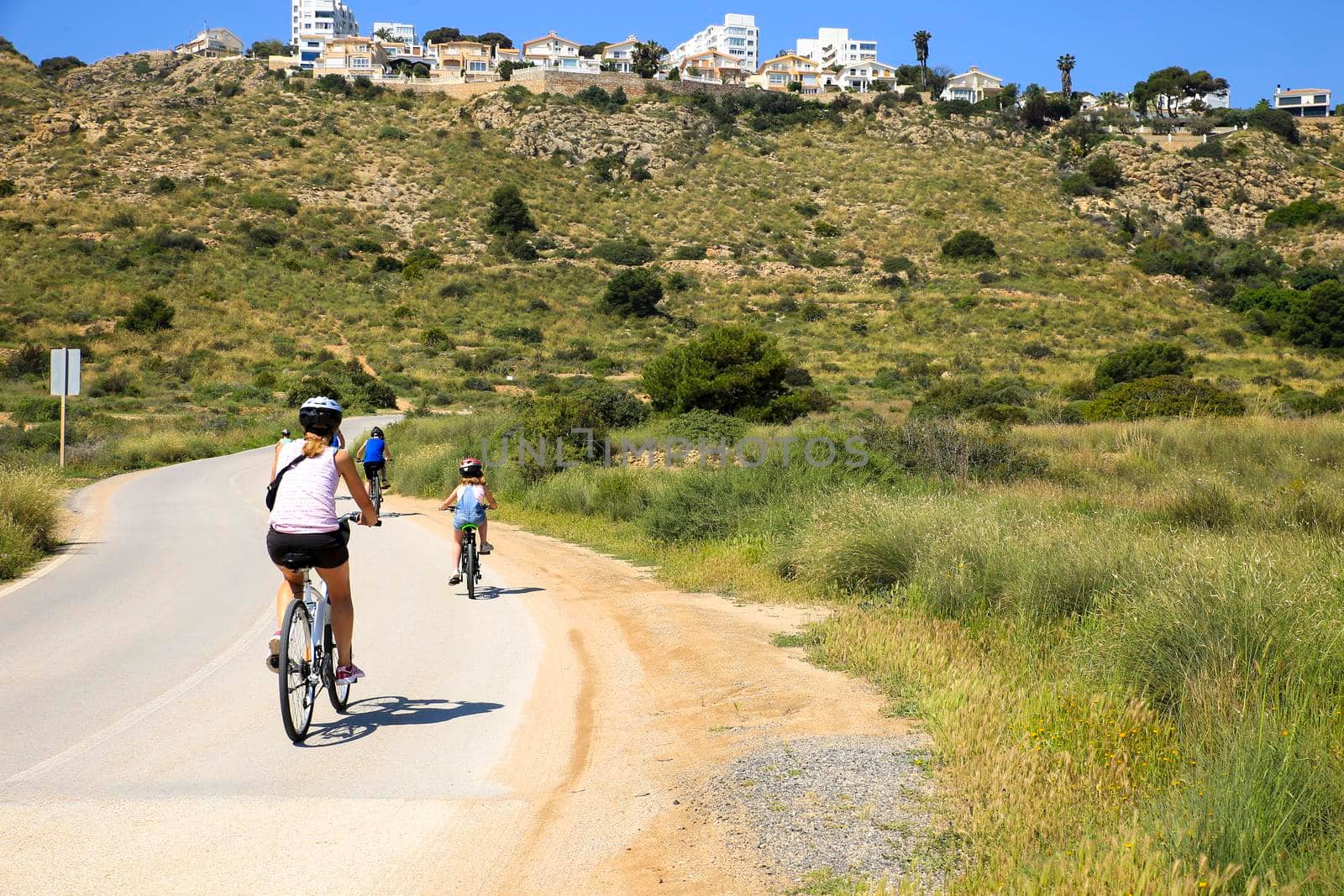 Santa Pola, Alicante, Spain- May 6, 2022: Cyclist riding along the road that borders little beaches of the Lighthouse in Santa Pola, Alicante