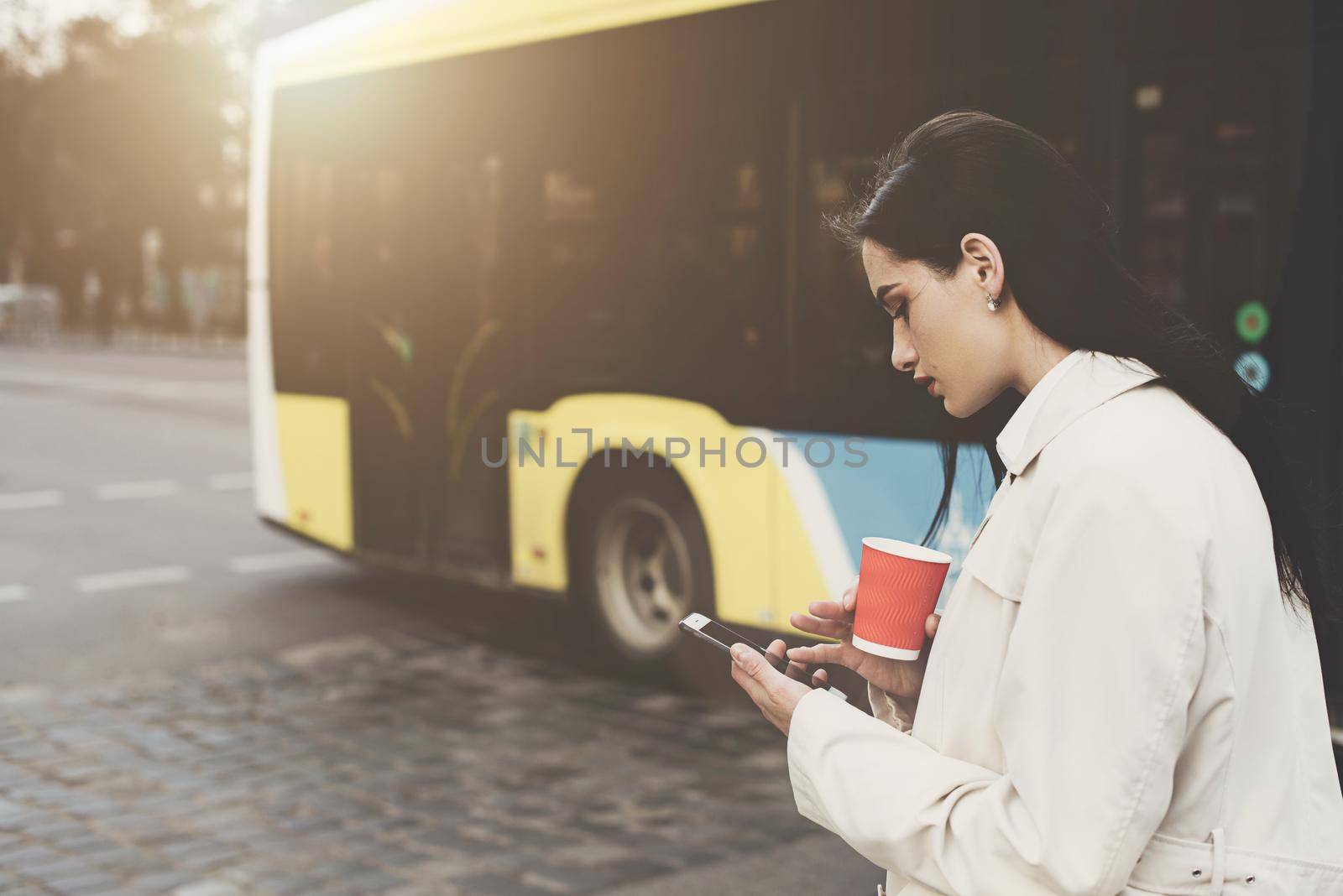 A woman on the street uses a mobile phone. online shopping. use of mobile applications. beautiful woman with long dark hair in a raincoat