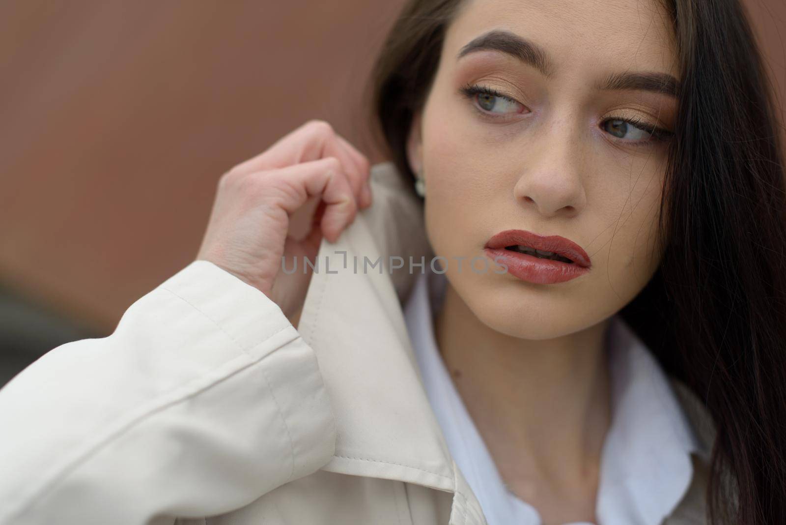 Outdoor portrait of a young beautiful fashionable lady wearing stylish coat . Model looking aside. Female fashion concept. City lifestyle. Close up. by Ashtray25