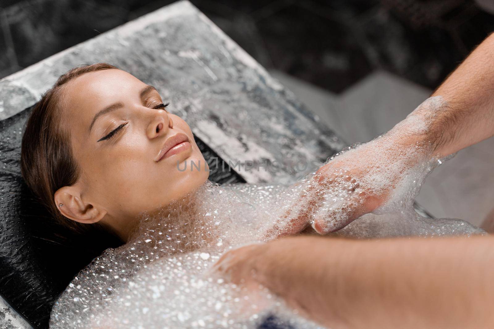 Close-up portrait of girl on foam peeling procedures in spa. Model is relaxing in Turkish hammam