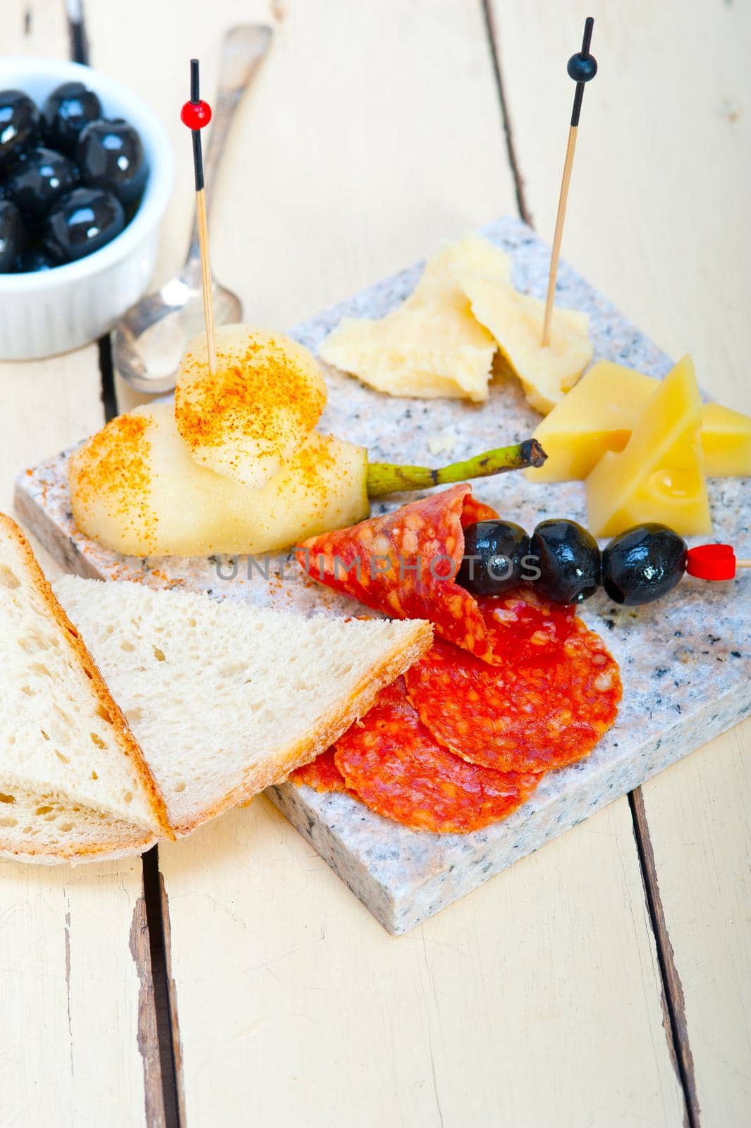 cold cut assortment cheese salami and fresh pears served on a granite stone