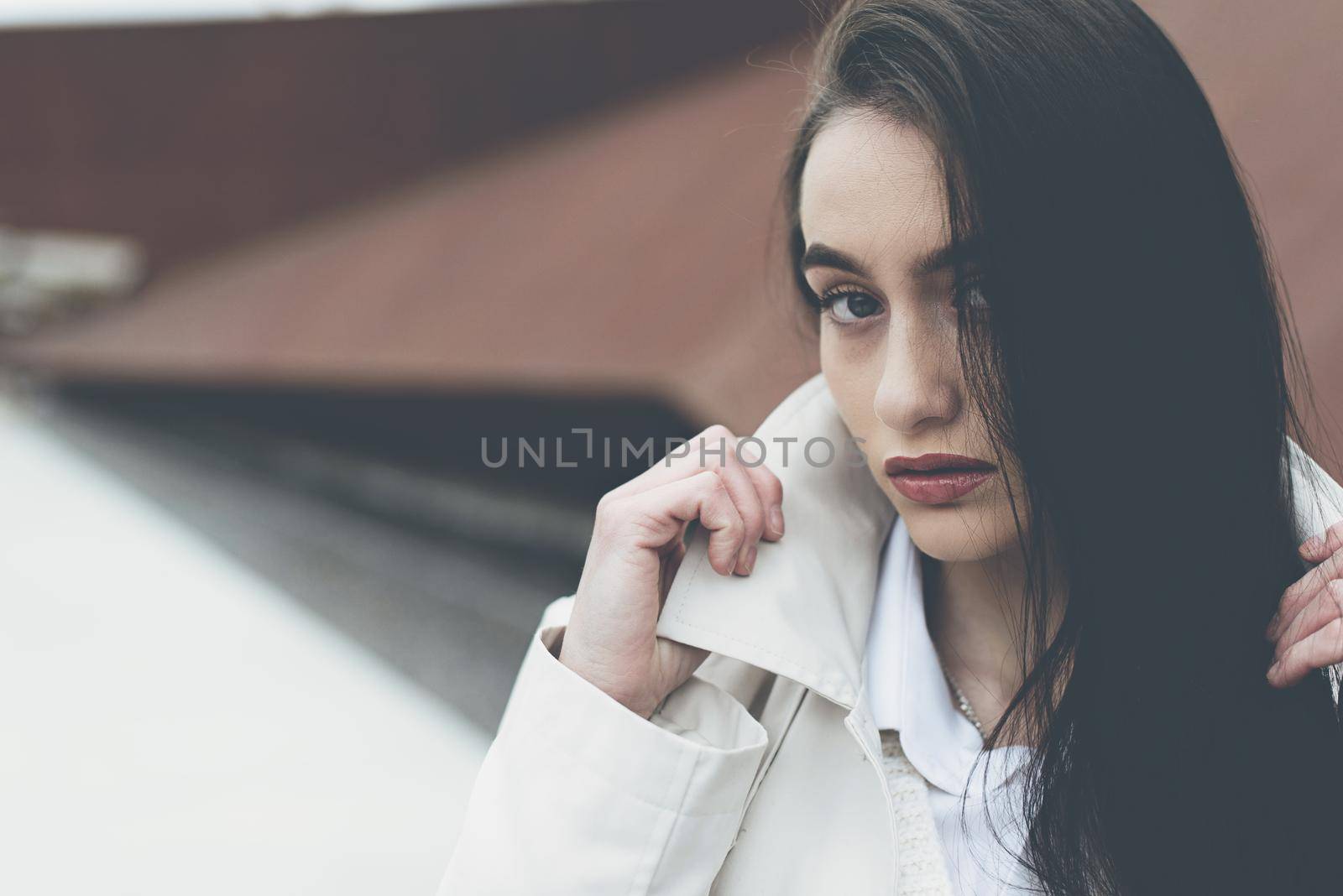 Outdoor portrait of a young beautiful fashionable lady wearing stylish coat . Model looking aside. Female fashion concept. City lifestyle. Close up. big plump lips