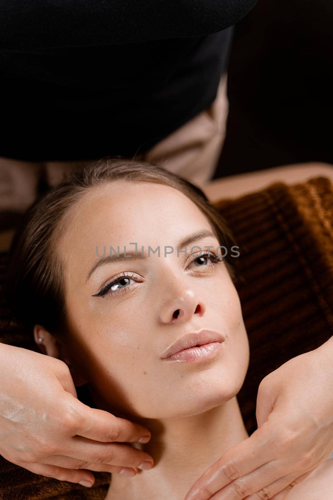 Masseur is making facial massage in spa for model with perfect skin. Beauty procedure. by Rabizo