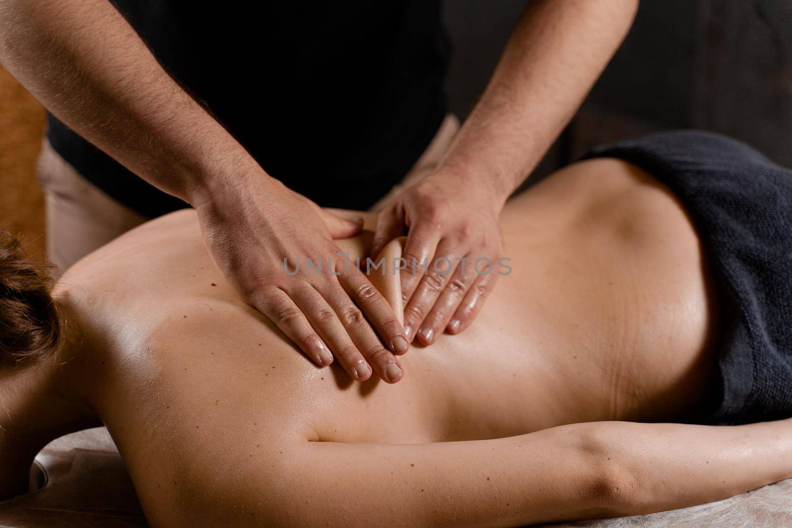 Attractive girl is relaxing on classic massage procedure in spa. Manual therapy. Masseur is doing back massage. by Rabizo