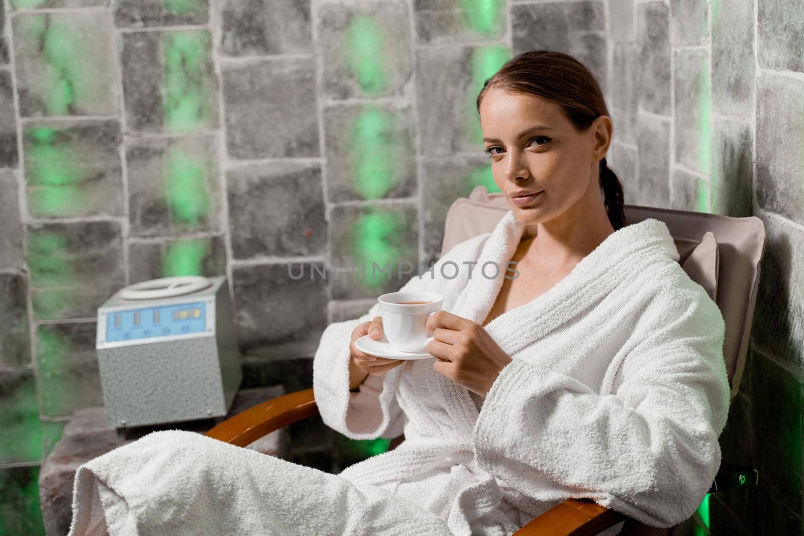 Inhalation therapy in salt room in spa. Young woman with cup of tea relaxing. by Rabizo