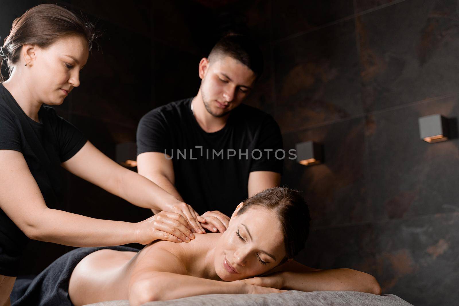 4 hands massage in spa. Two masseurs are making four hands relaxing massage with oil for girl. Relaxation. Manual therapy.