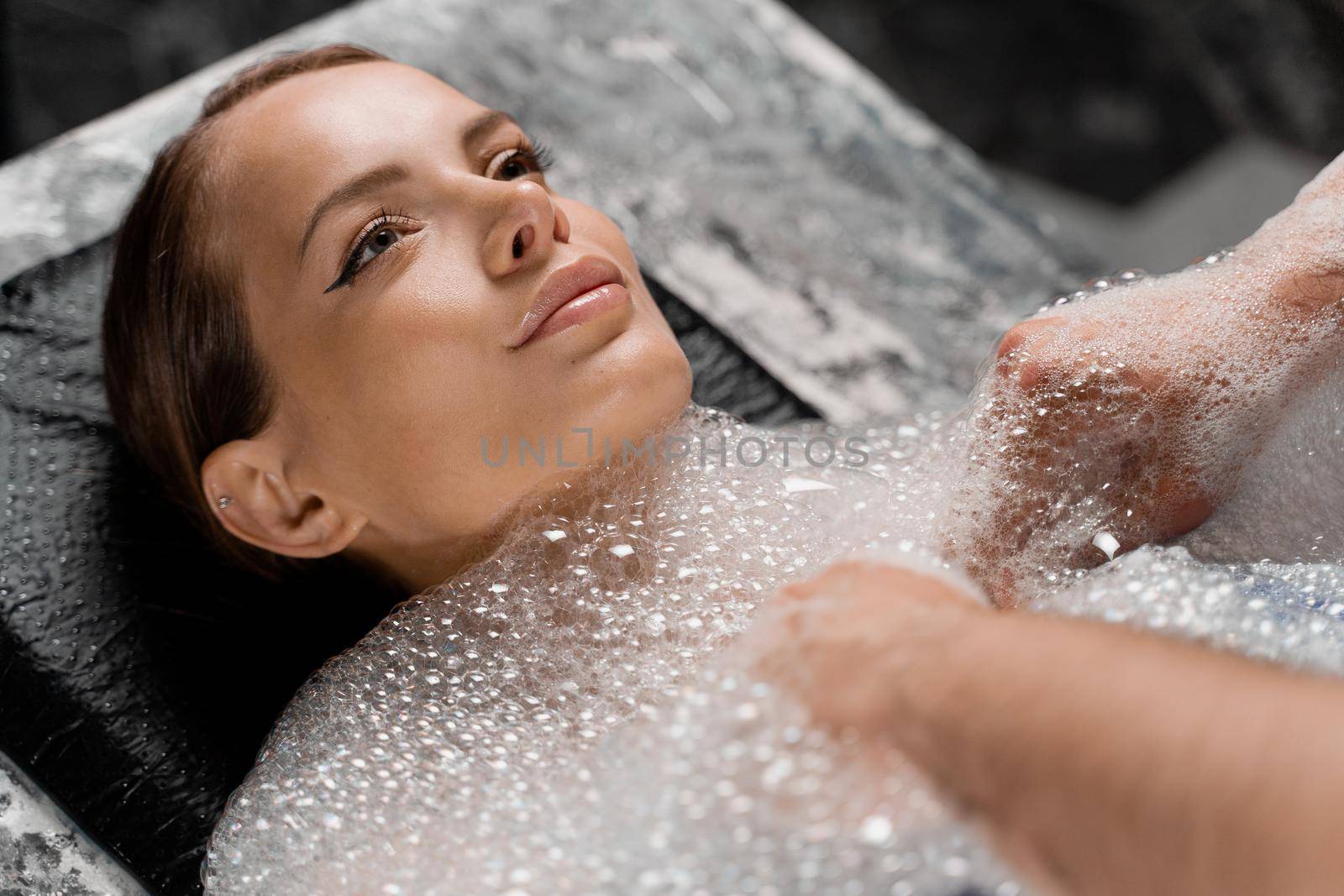 Close-up portrait of girl on foam peeling procedures in spa. Model is relaxing in Turkish hammam. by Rabizo