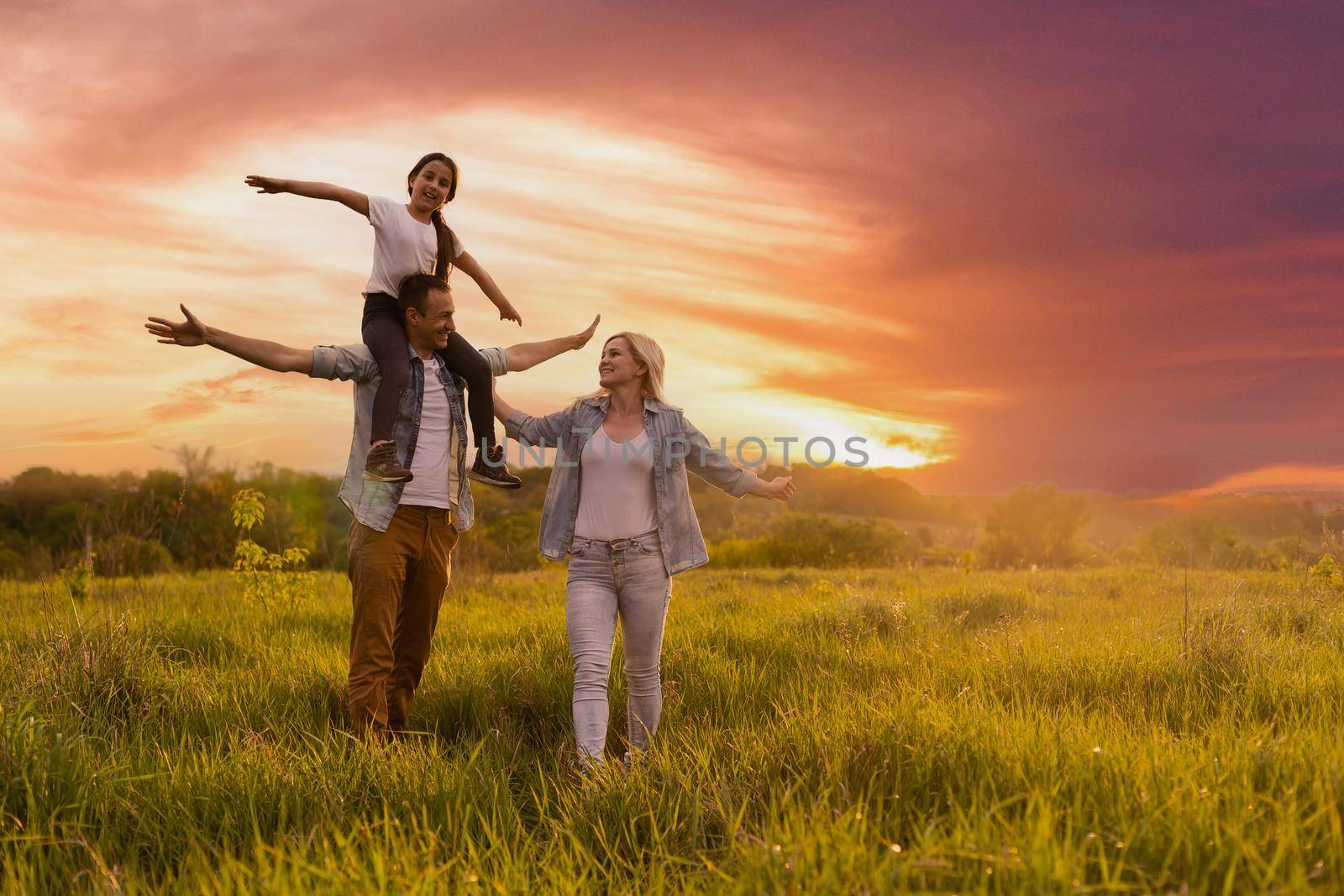 Happy family: mother father and child daughter on nature on sunset.