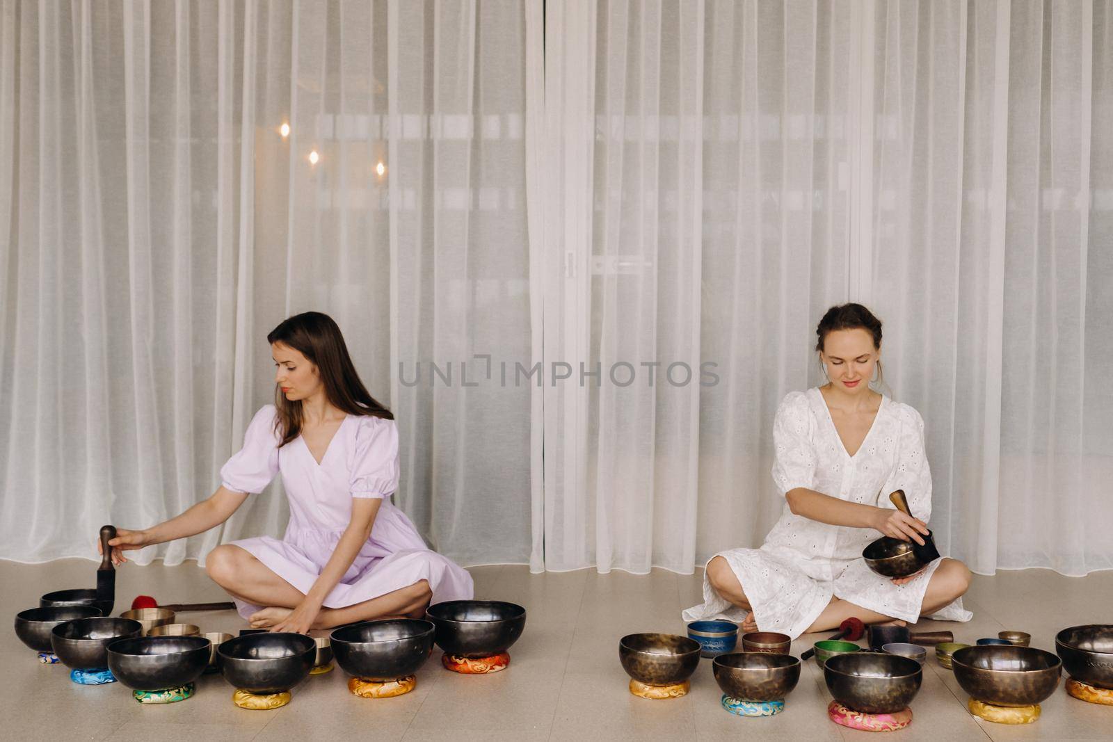 Two female yoga teachers play on Tibetan bowls in the gym during a yoga retreat.