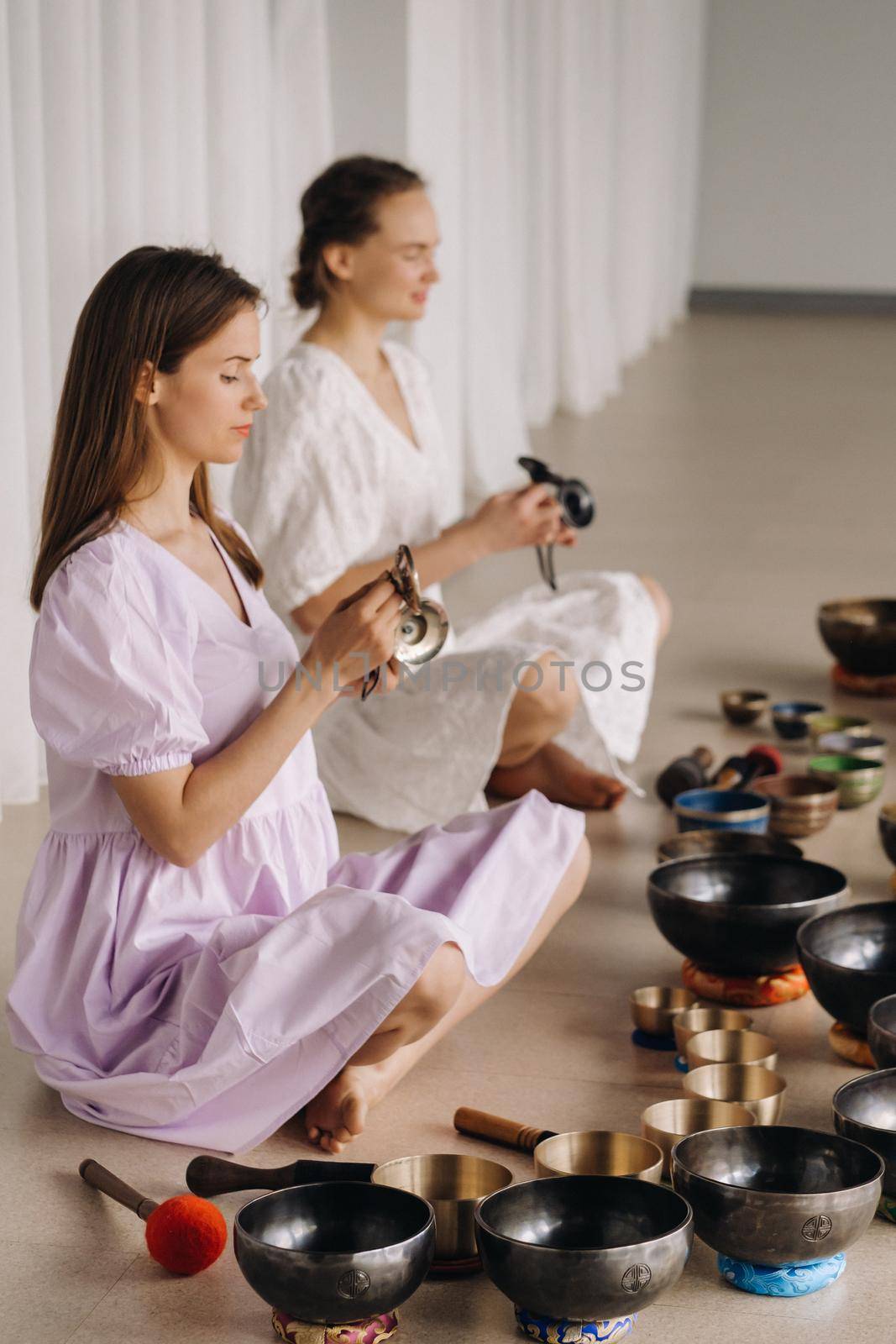 Two female yoga teachers play on Tibetan bowls in the gym during a yoga retreat.