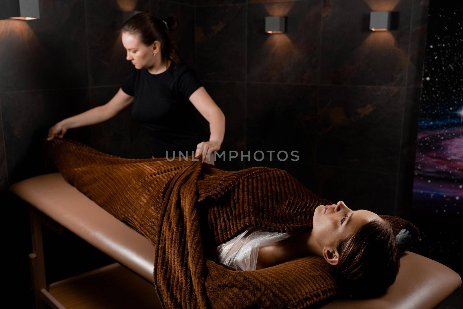 Full body wrap in warm blanket after chocolate massage beauty treatment for female model in spa