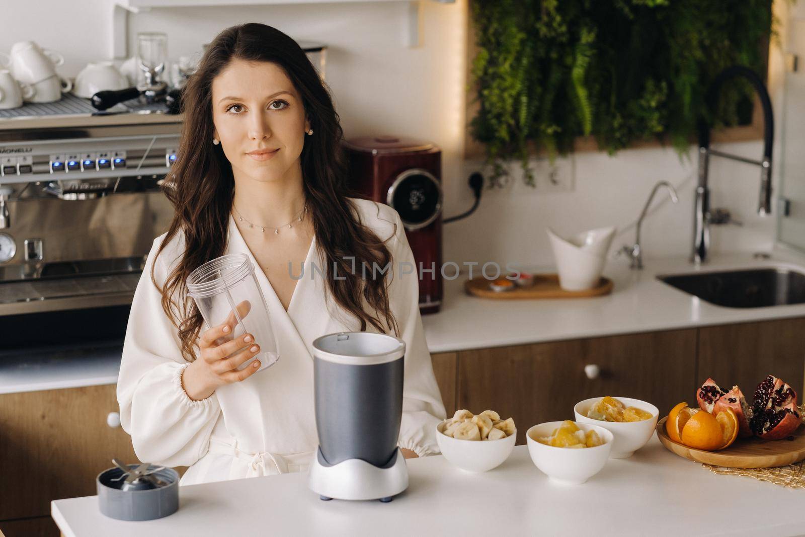 a girl makes a detox cocktail of fruit in the kitchen . Diet for weight loss.