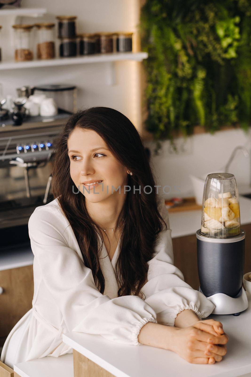 Portrait of a girl who makes a delicious fruit cocktail in the kitchen. Diet for weight loss.