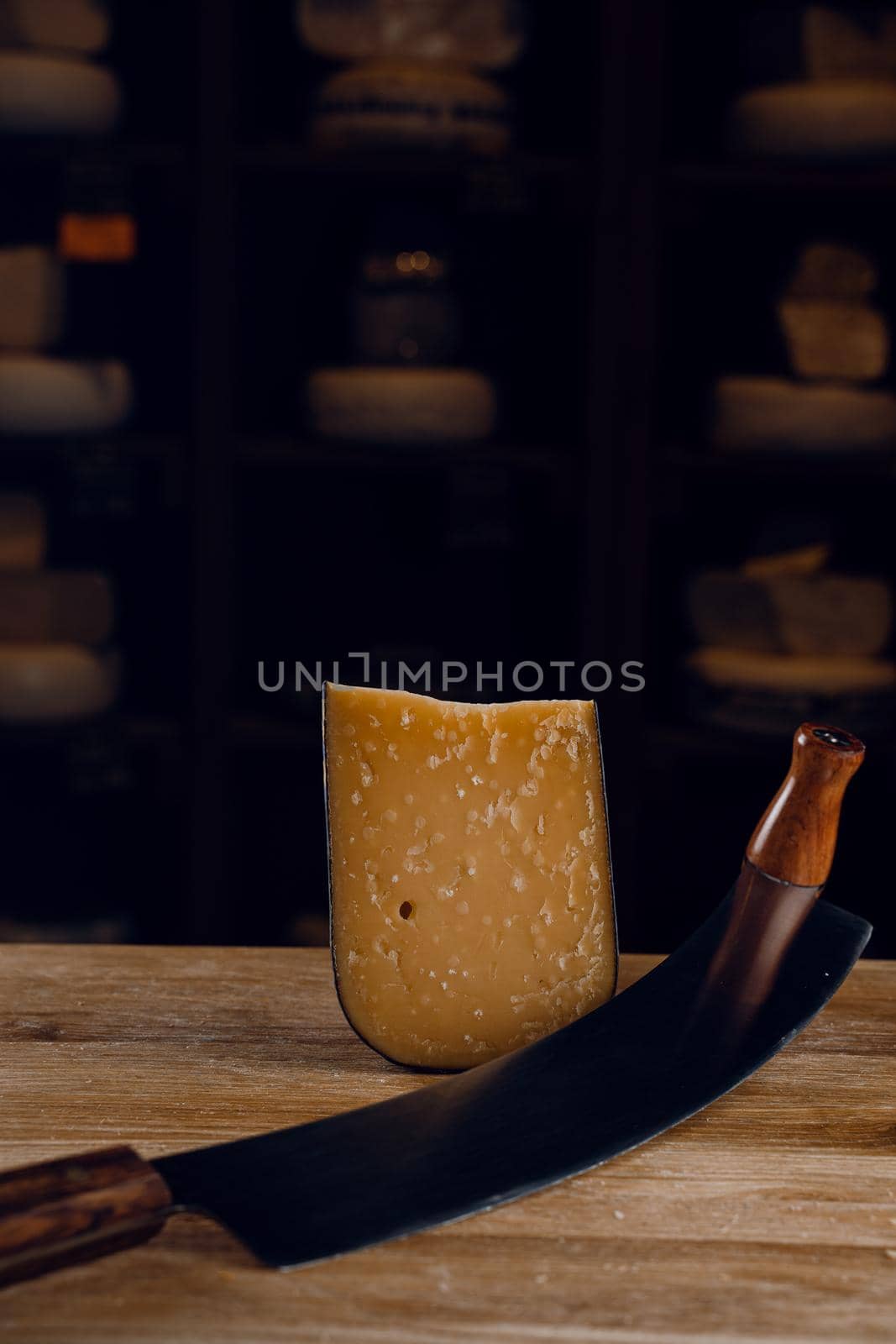 Parmesan hard aged cheese with dutch cheese knife on dark background. Snack tasty piece of cheese for appetizer. by Rabizo