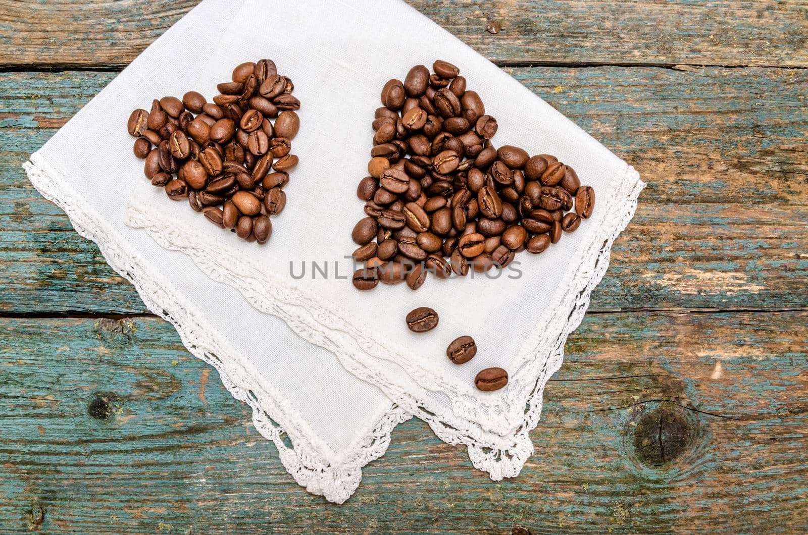 Two hearts made from coffee beans on wooden background. From a series Coffee time