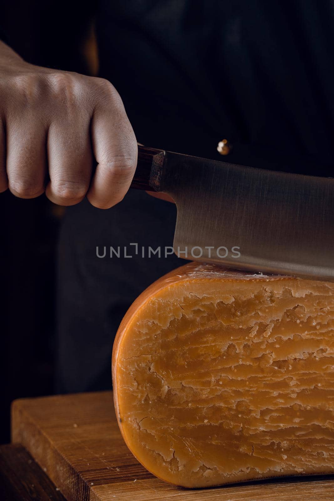 Close-up slicing aged cheese parmesan with crystals using a cheesy dutch knife. Hard cheese with knife. by Rabizo