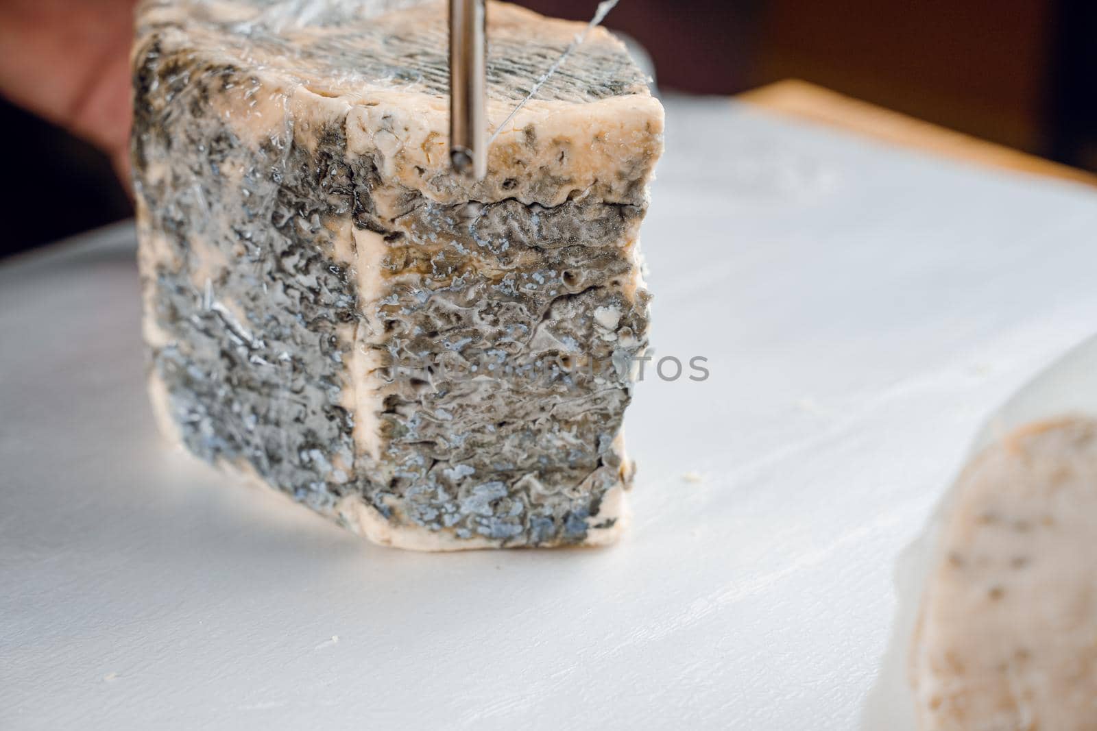 String for slicing blue cheese. Mix of cheeses on plate. Slicing dorblu, gorgonzola, roquefort. French gourmet cuisine.