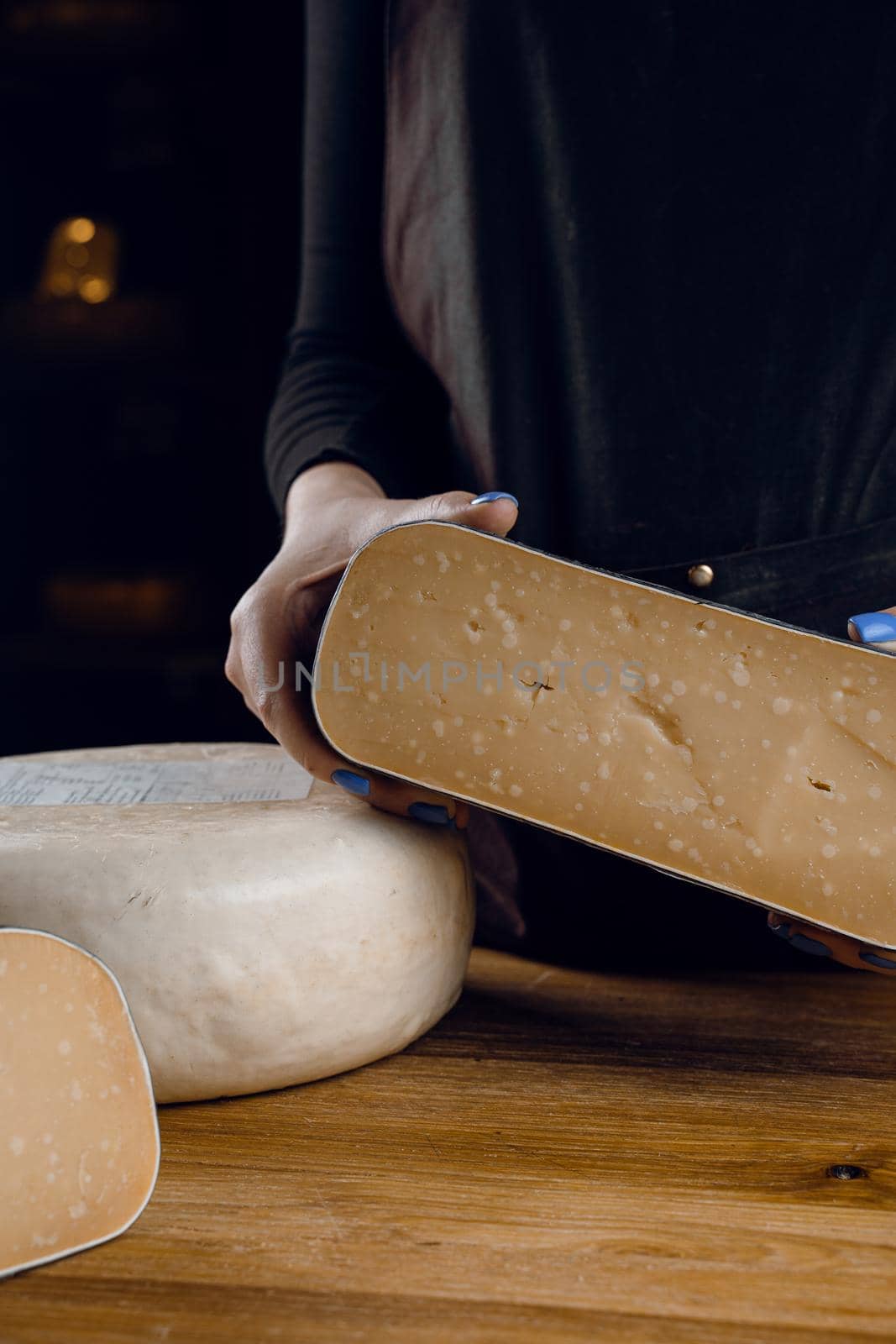 Holding goat cheese wheel and big pieces of it. Mix of cheeses from goat milk.