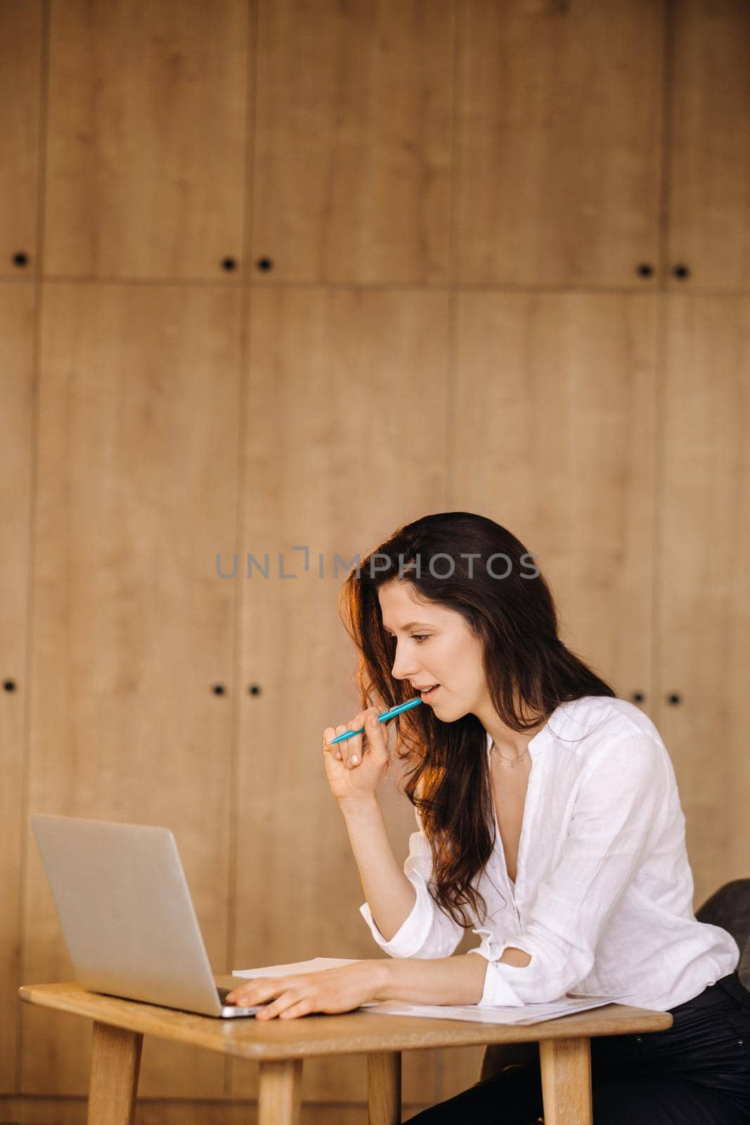 Beautiful woman sitting in the office working on a laptop by Lobachad