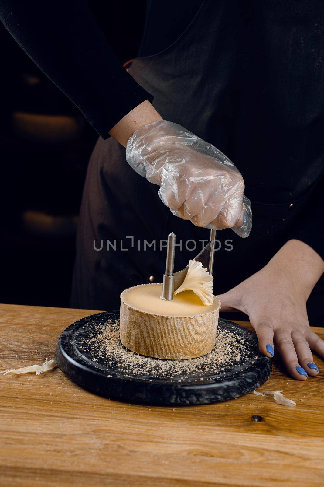 Shaving tete de moine cheese using girolle knife. Monks head. Variety of Swiss semi-hard cheese made from cows milk.