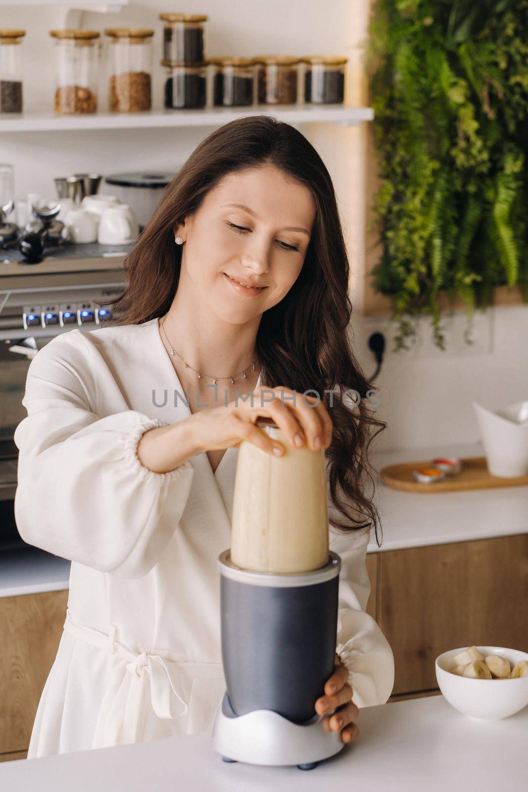 a girl makes a cocktail in a fruit blender in the kitchen. Diet for weight loss by Lobachad