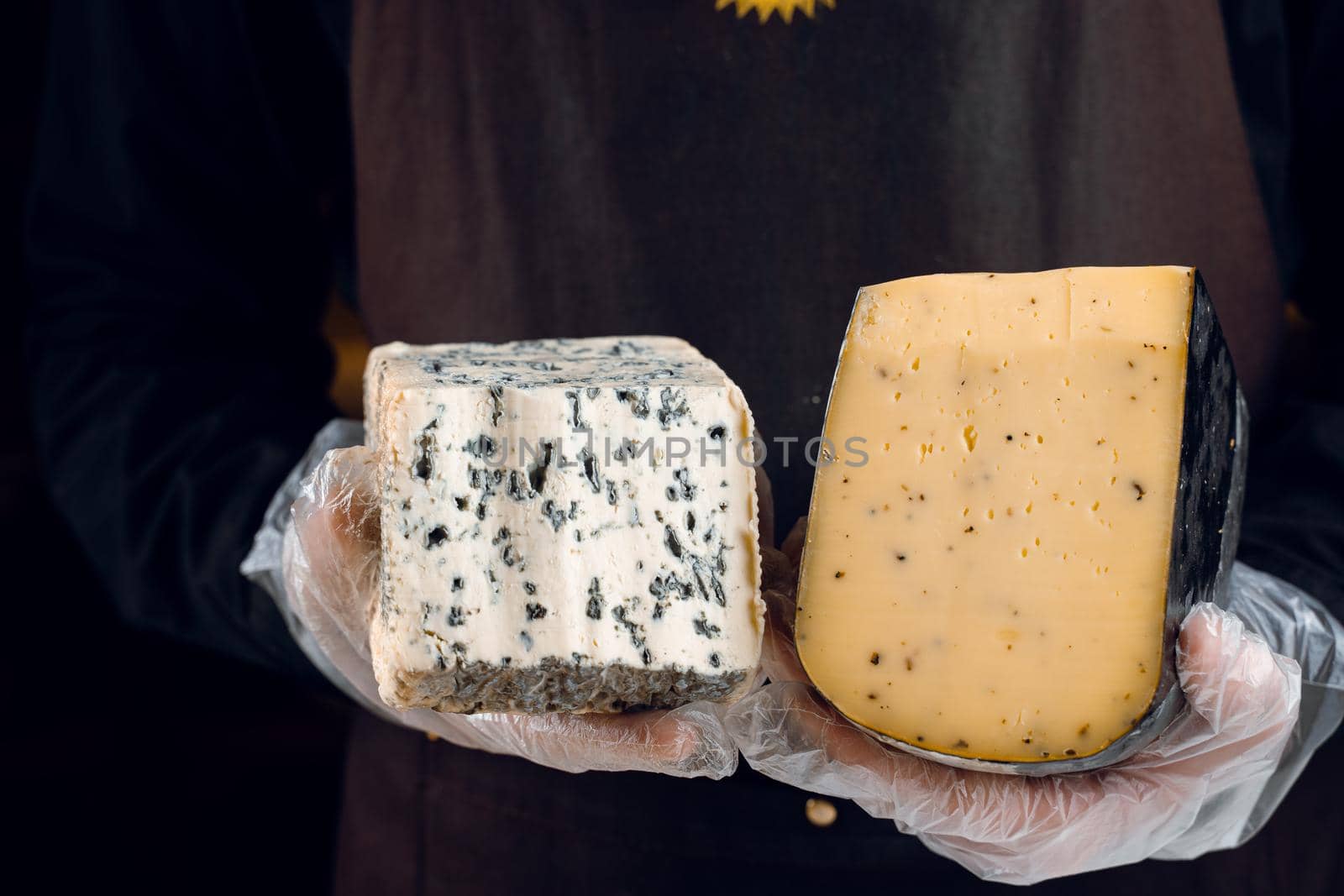 Blue cheese and gouda with italian herbs in hands. Holding dorblu, gorgonzola, roquefort. French gourmet cuisine.