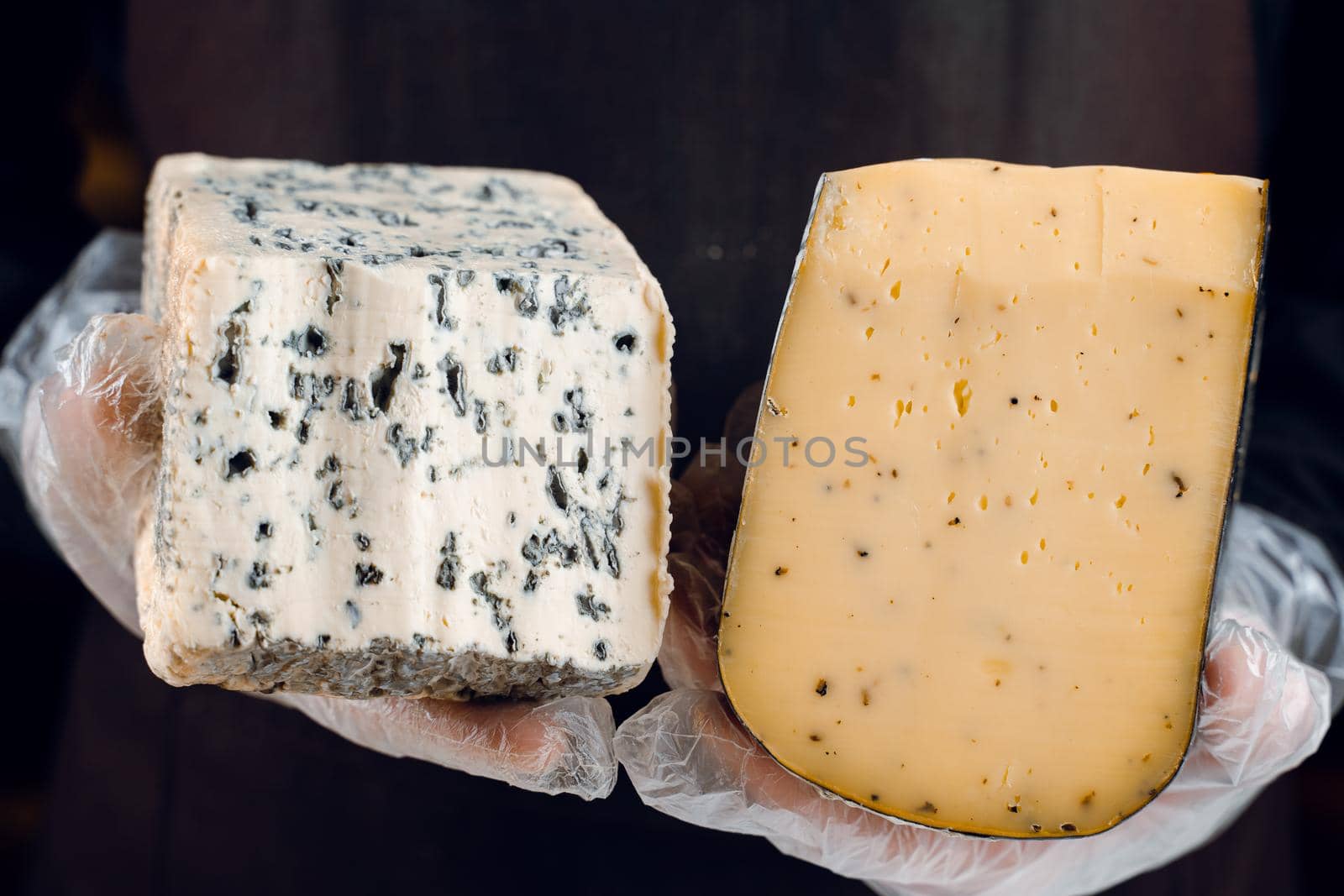 Blue cheese and gouda with italian herbs in hands. Holding dorblu, gorgonzola, roquefort. French gourmet cuisine.