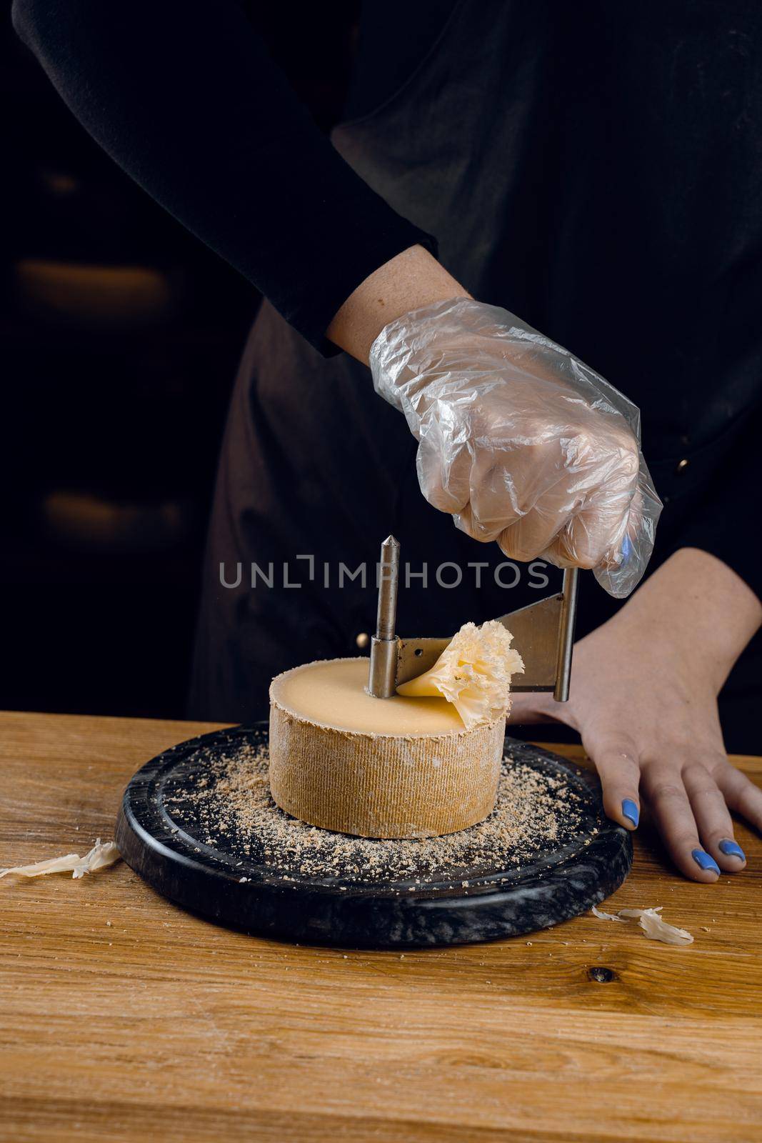 Shaving tete de moine cheese using girolle knife. Monks head. Variety of Swiss semi-hard cheese made from cows milk by Rabizo