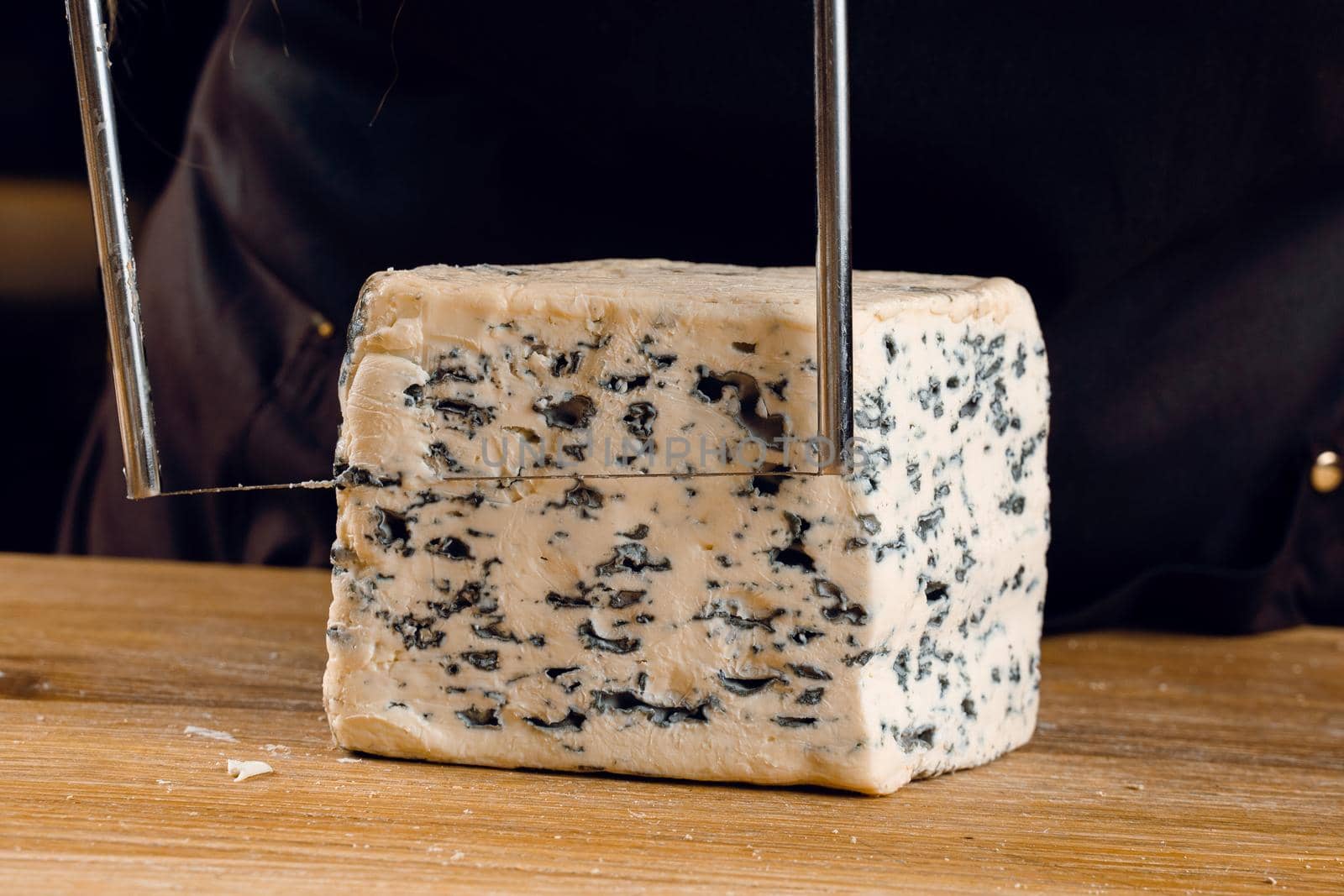 String for slicing blue cheese. Mix of cheeses on plate. Slicing dorblu, gorgonzola, roquefort. French gourmet cuisine