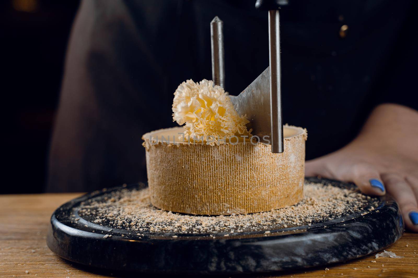 Shaving tete de moine cheese using girolle knife. Monks head. Variety of Swiss semi-hard cheese made from cows milk.