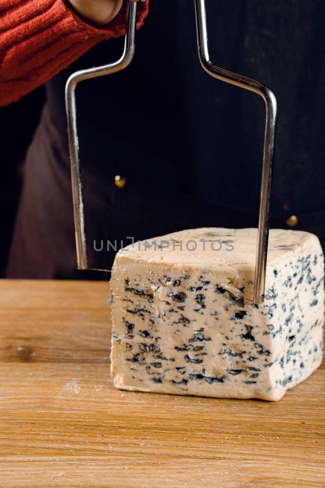 String for slicing blue cheese. Mix of cheeses on plate. Slicing dorblu, gorgonzola, roquefort. French gourmet cuisine